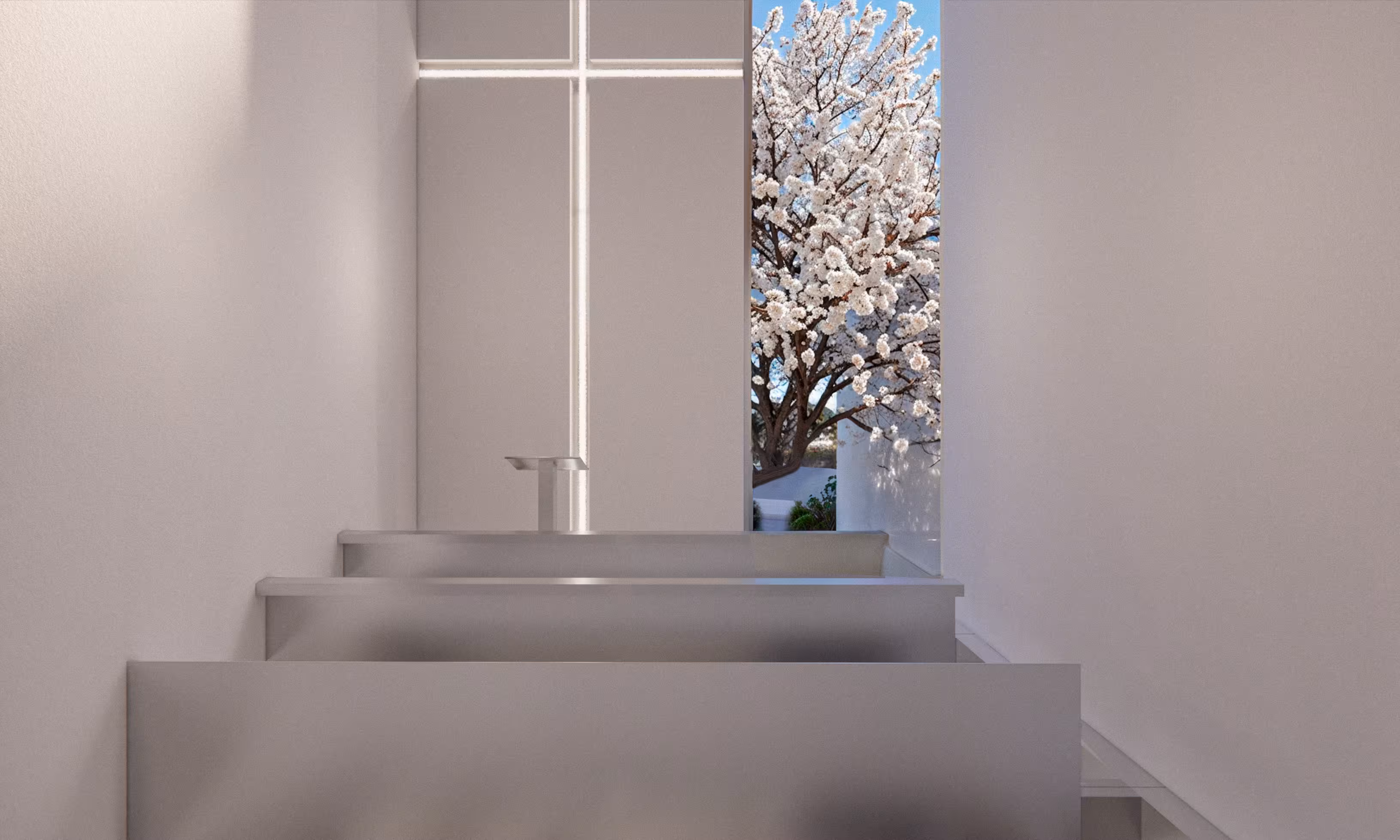 Lavabos modernos de acero inoxidable con grifos debajo de una ventana con vista a un árbol floreciente.