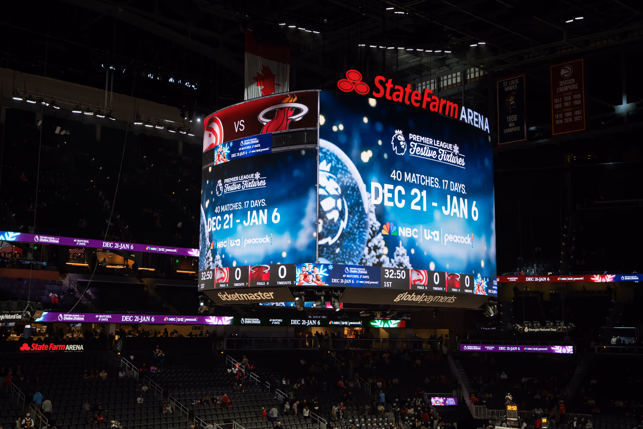 State Farm Arena scoreboard showing a basketball game between Atlanta Hawks and Miami Heat tied at 0-0 with 32:50 remaining in the first quarter, and an advertisement for Premier League Festive Fixtures from Dec 21 to Jan 6.