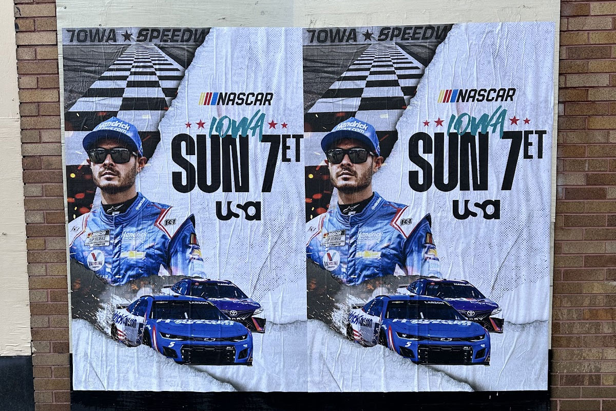 Poster featuring a race car driver in blue racing gear and sunglasses with two blue race cars and text 'NASCAR Iowa Sun 7 ET USA' with a checkered flag background.