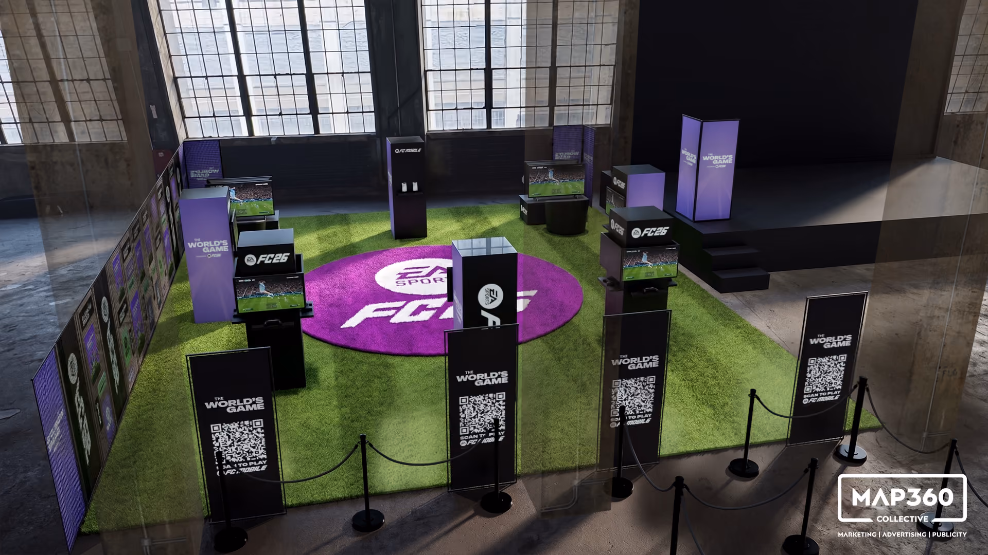 Indoor event space with green turf floor area surrounded by black stands displaying screens and QR codes promoting a gaming event labeled 'The World's Game' and featuring the EA SPORTS FC26 logo on a purple circular mat in the center.