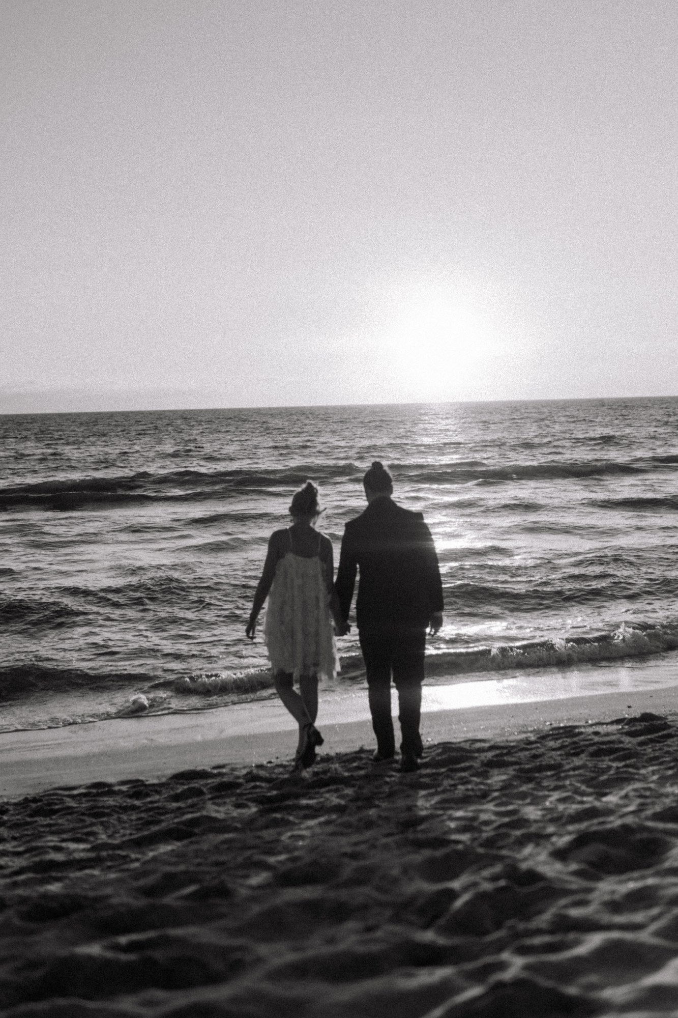 Bride and groom beach walk at sunset, tender closing moment