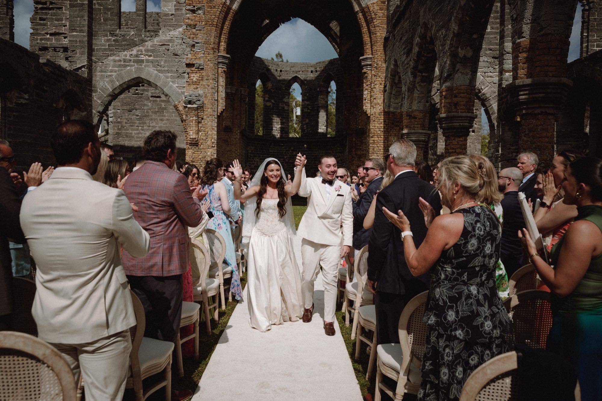 Bride and groom recessional through historic stone ruins at Bermuda destination wedding