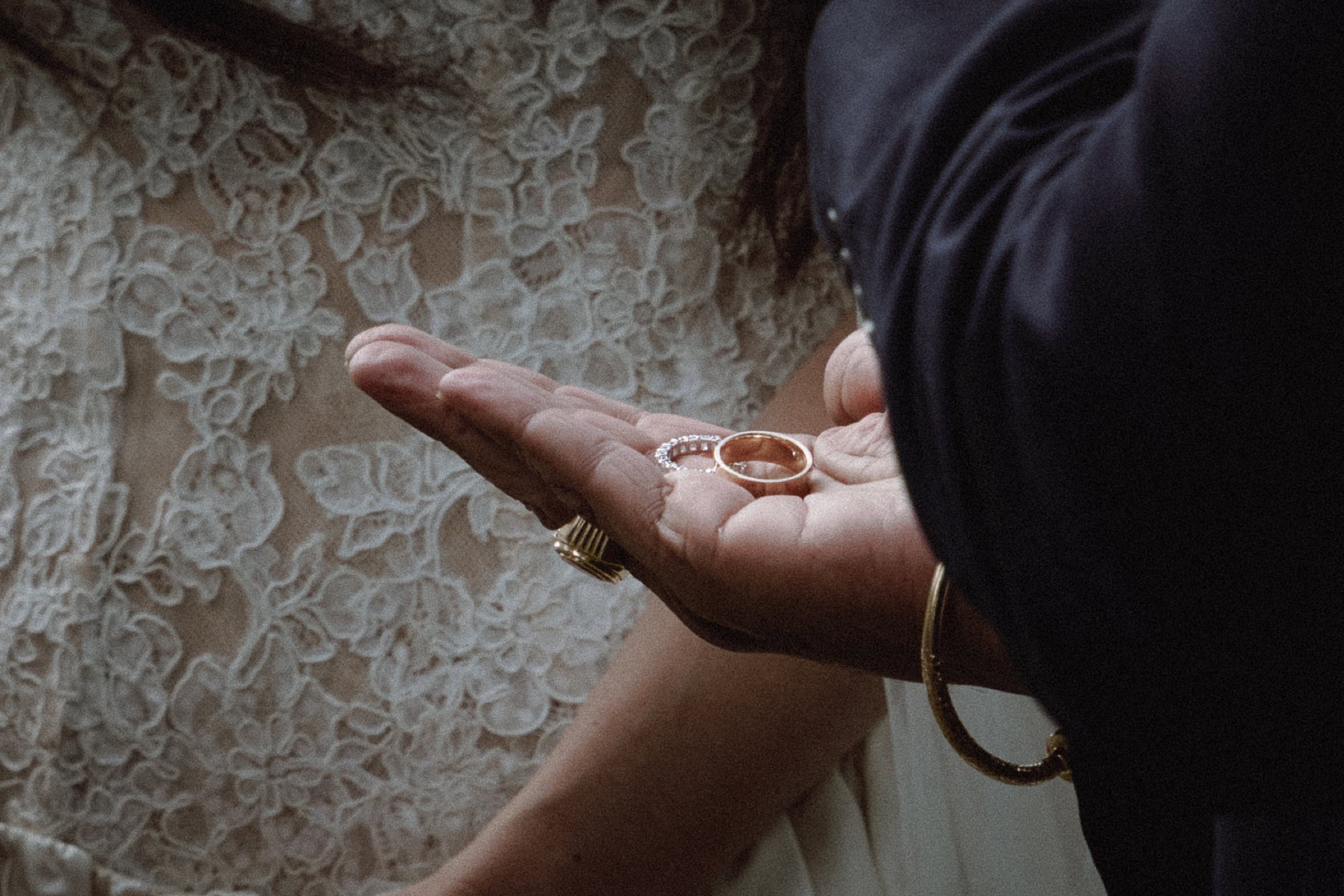 Close-up detail of wedding bands held in hand during ceremony