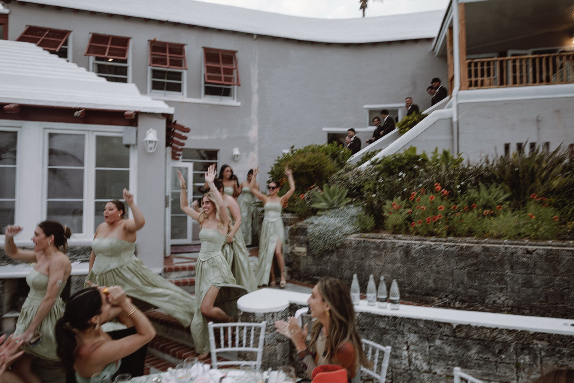 Bridesmaids celebrating with raised hands at oceanfront Bermuda reception
