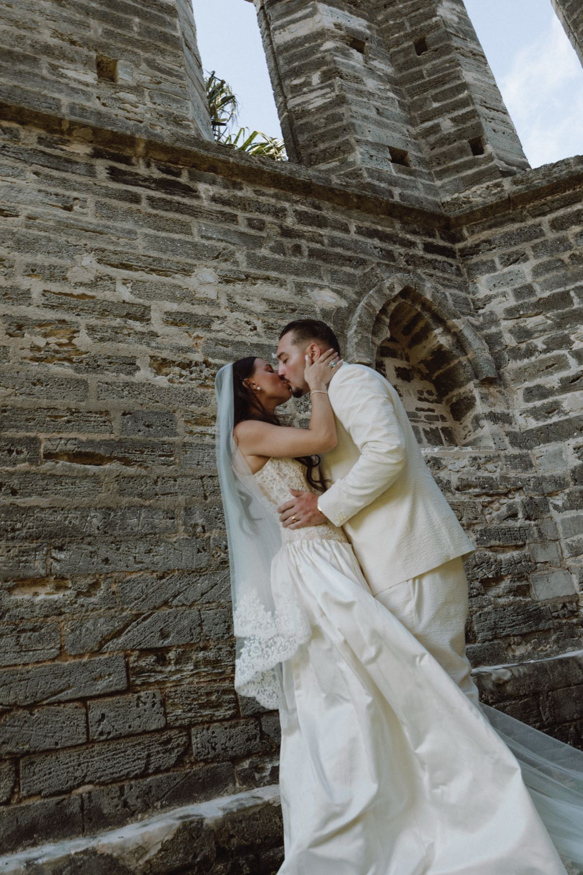 Cinematic low angle kiss between bride and groom at gothic stone ruins Bermuda wedding