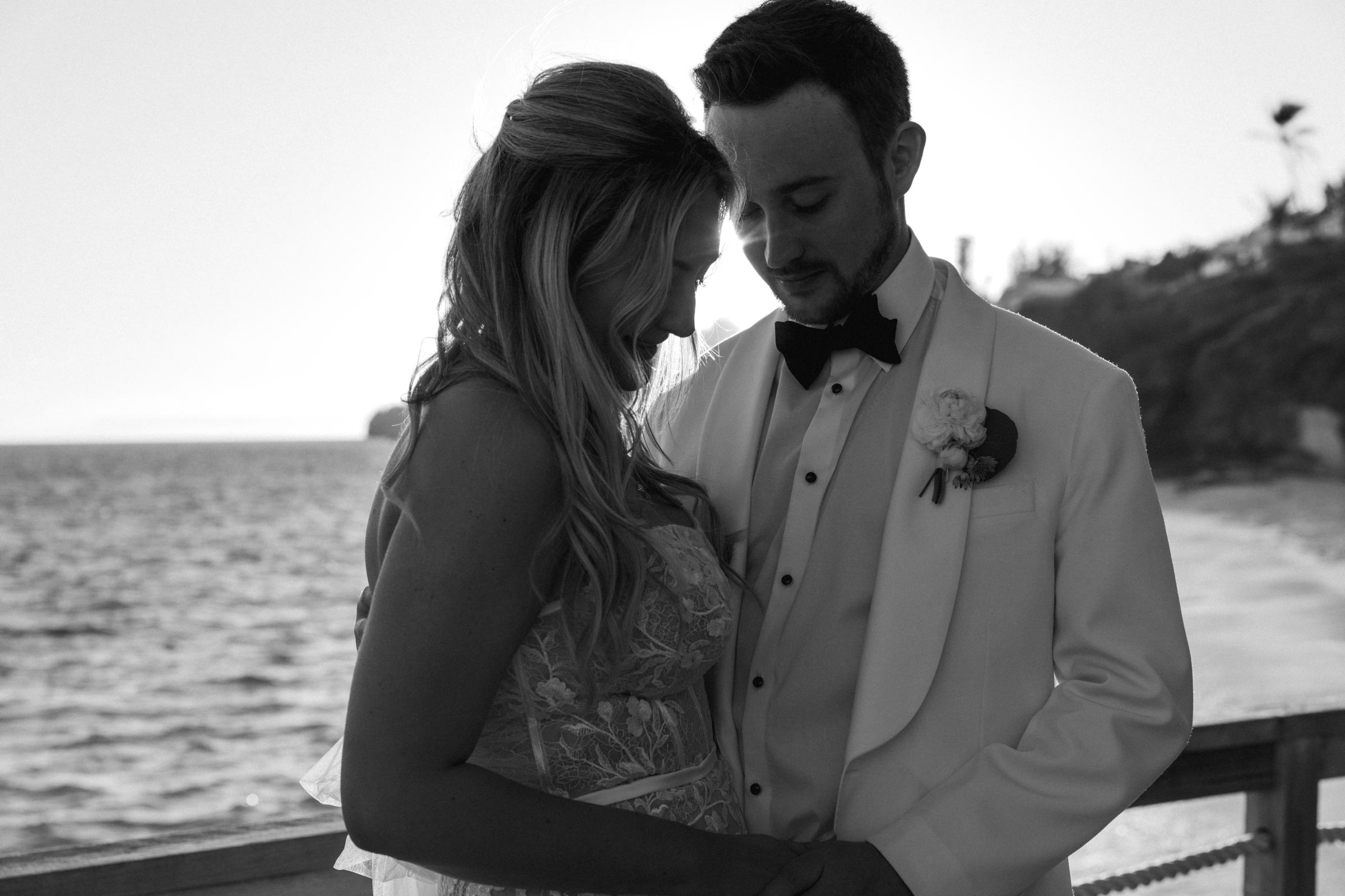 Black and white intimate close portrait of couple at golden hour beside Bermuda ocean