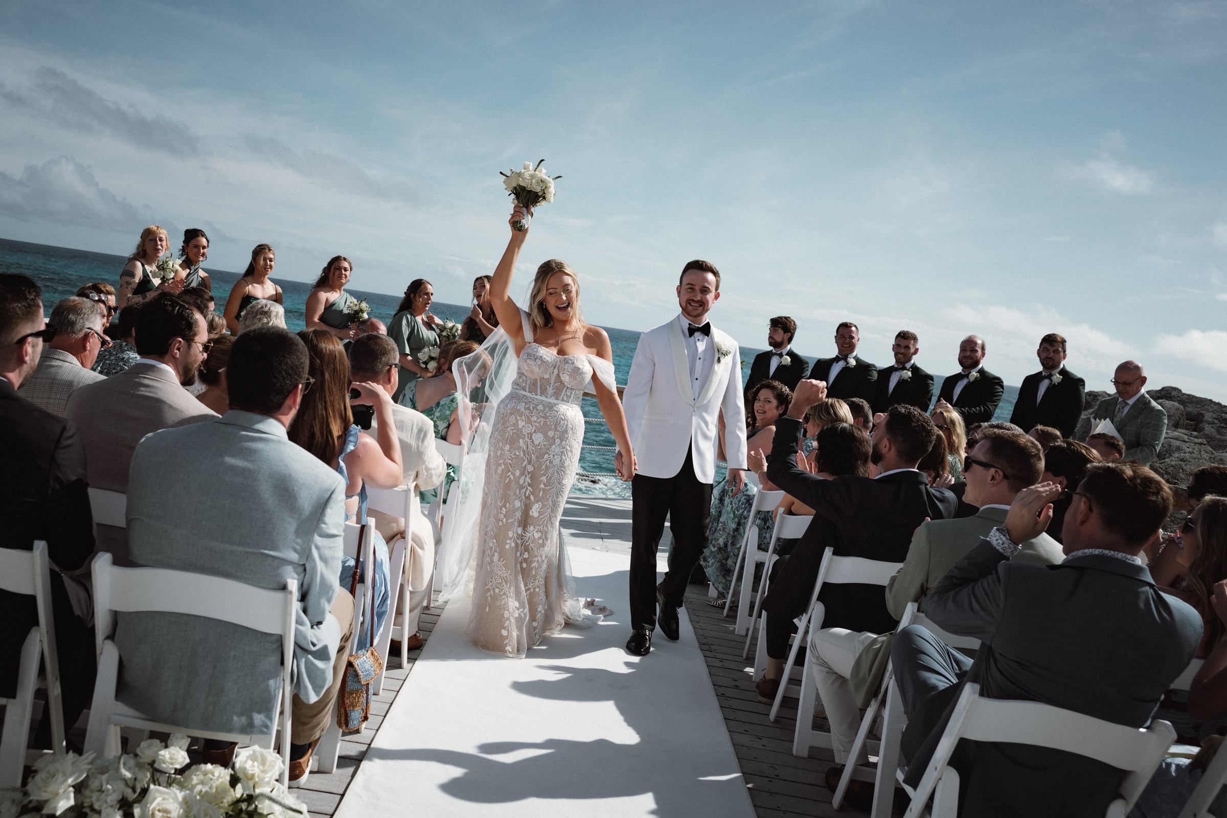 Joyful bride and groom recessional with raised bouquet at Bermuda wedding ceremony