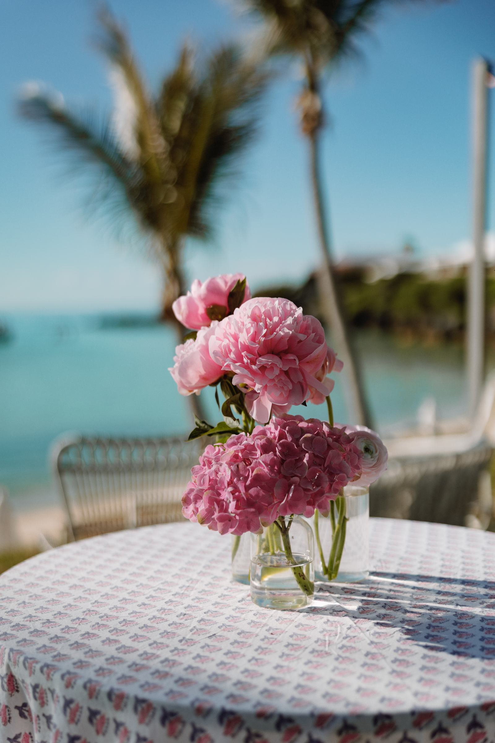 Pink peonies on a linen table with the Bermuda ocean soft behind them