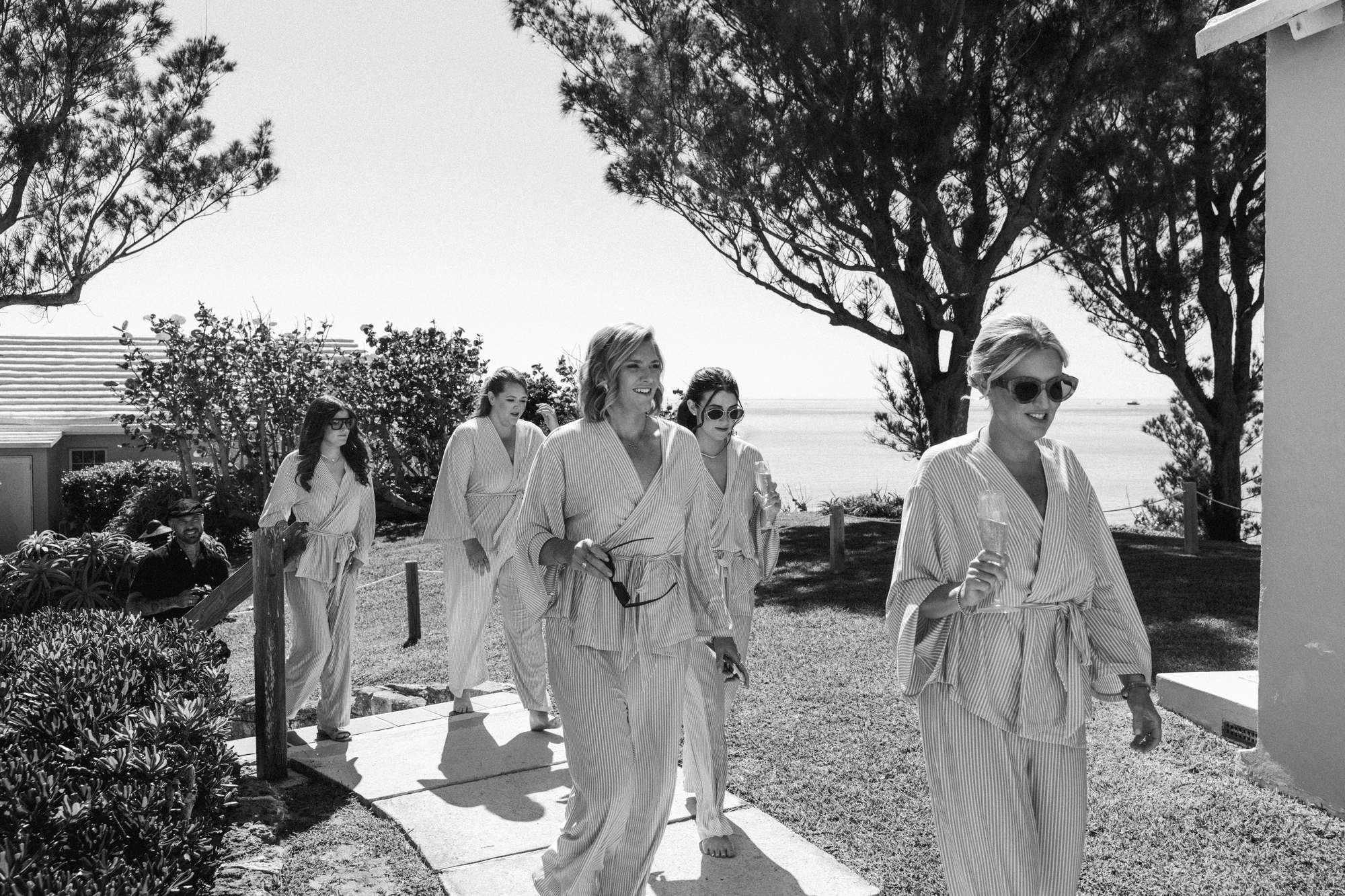 Black and white photograph of the bridal party walking down to the ocean in robes