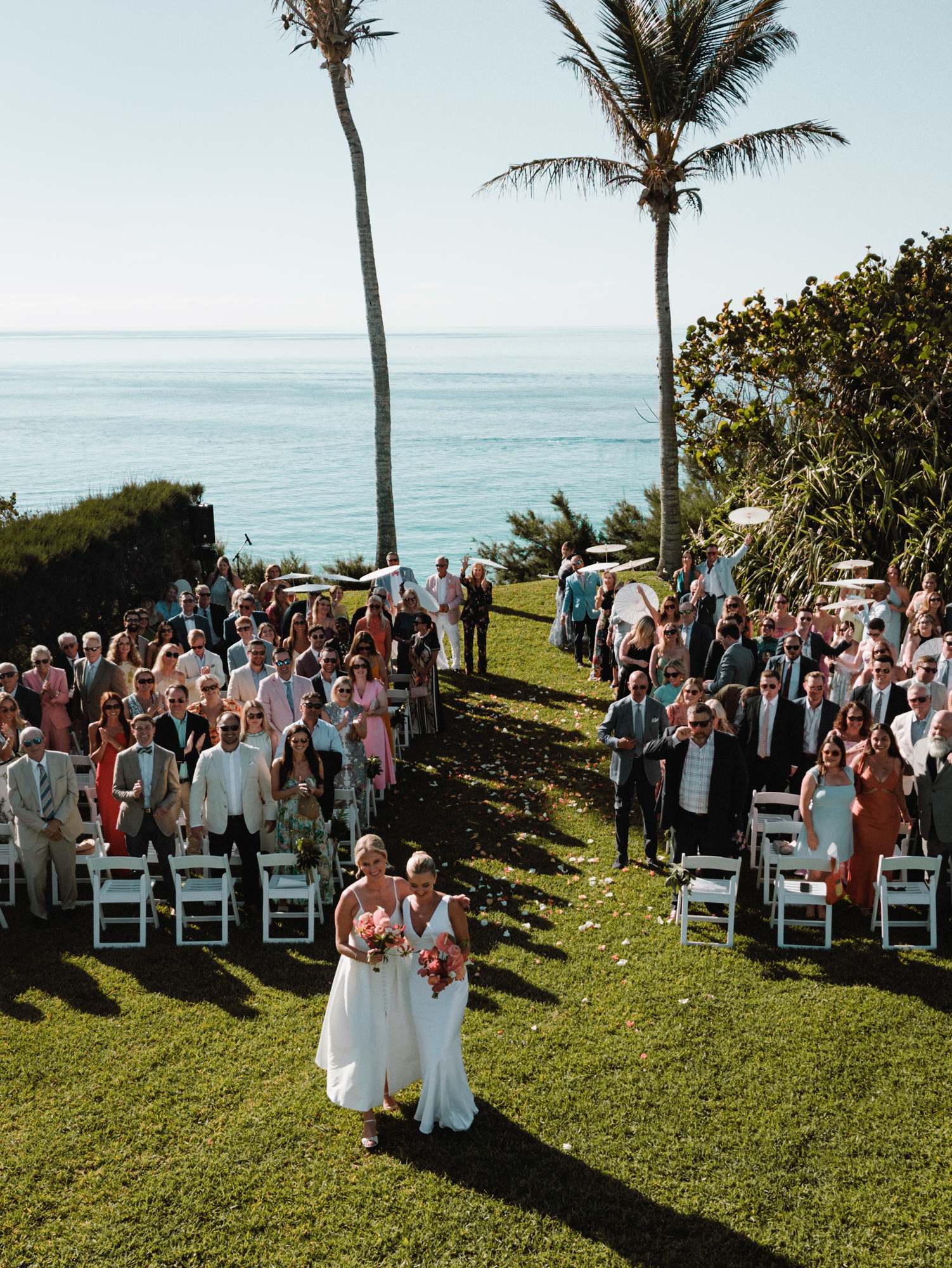 Processional down the grass aisle as guests stand at a Bermuda cliffside ceremony