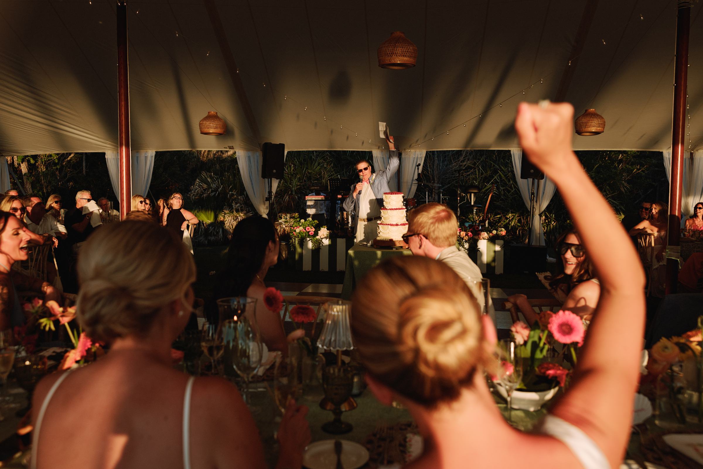 Guests cheering with a fist raised during speeches at a Bermuda wedding reception