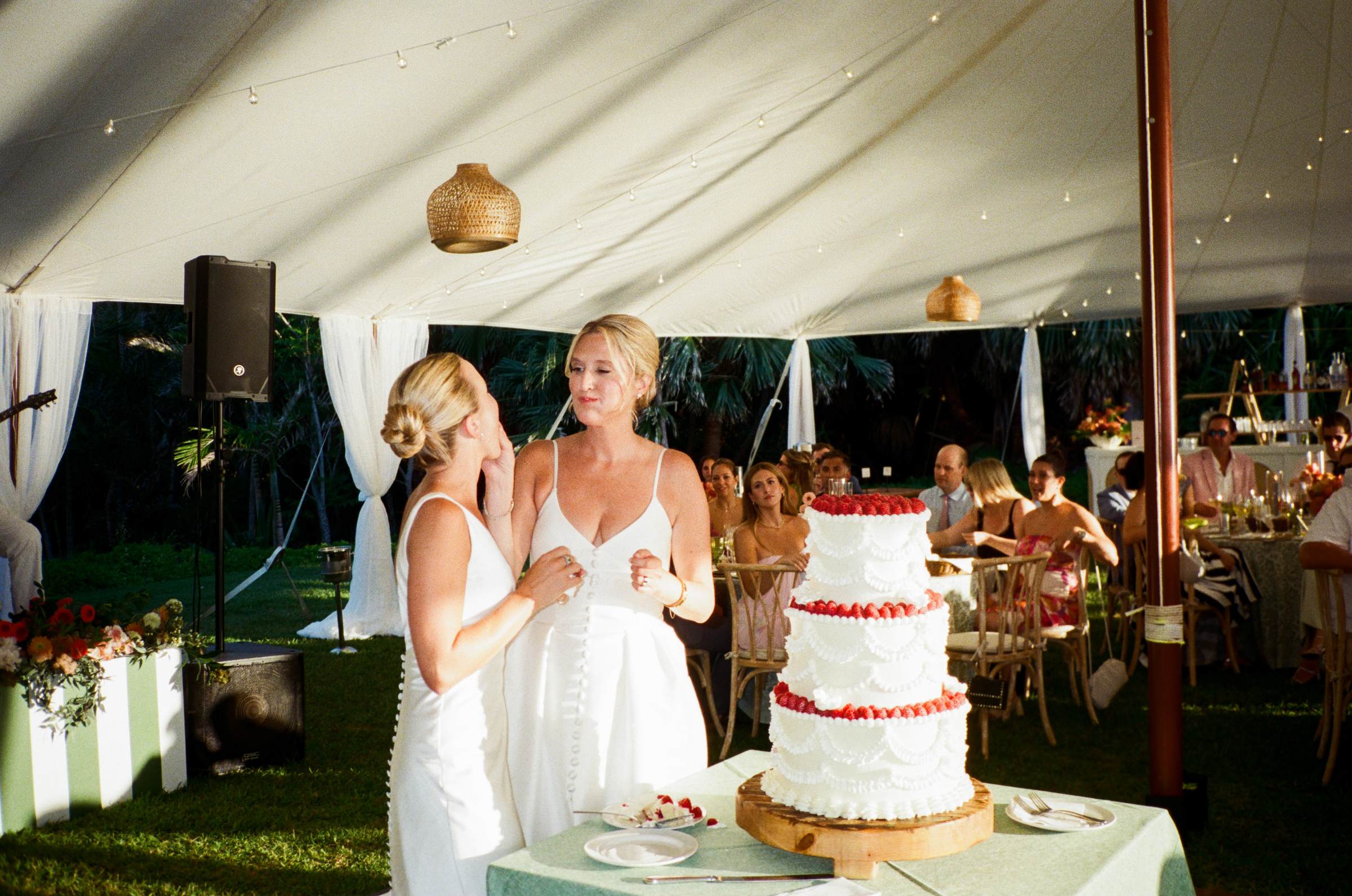 Two brides cutting the wedding cake inside the tent at their Bermuda reception