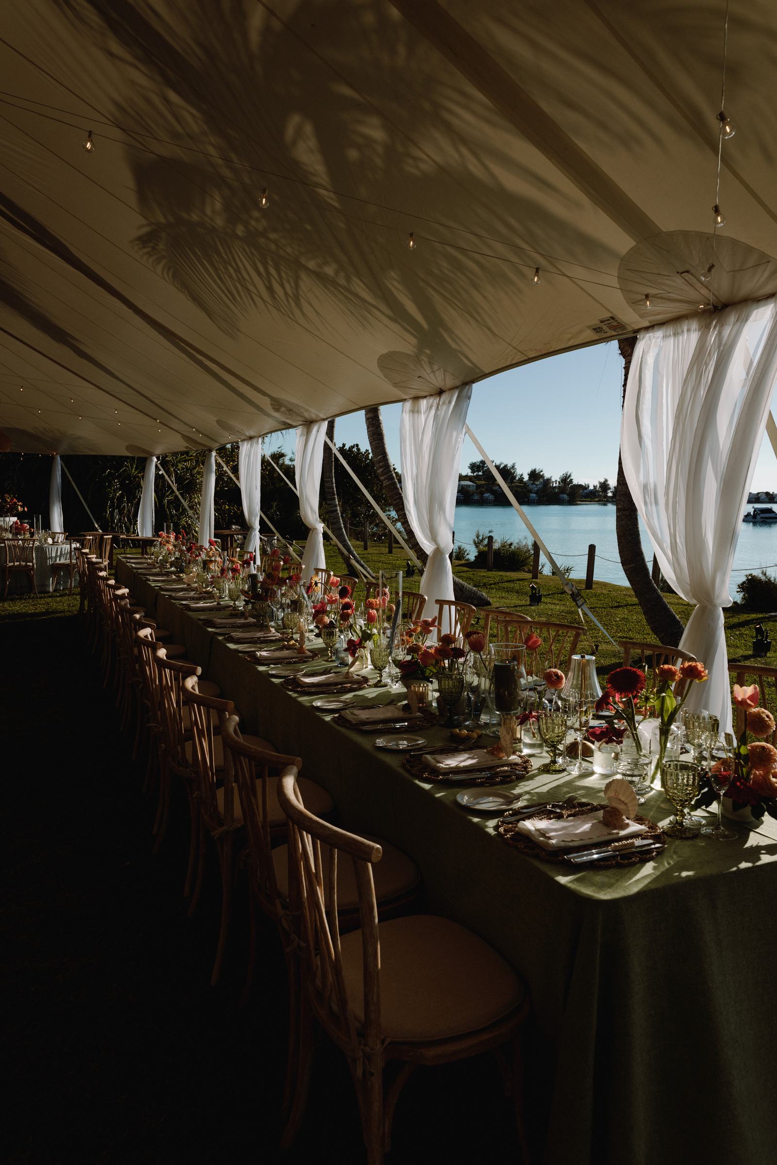 Long banquet table set under a sailcloth tent overlooking the Bermuda ocean