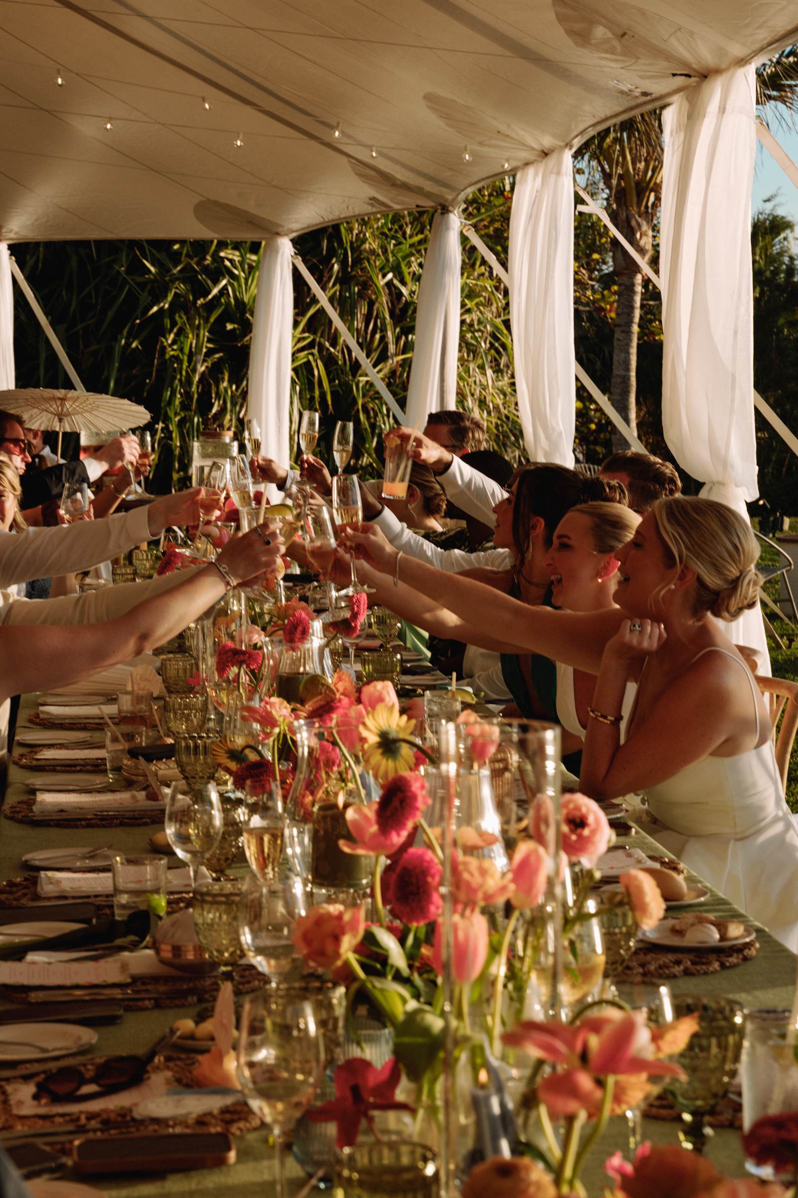 Toast down the long reception table with tropical flowers in the foreground
