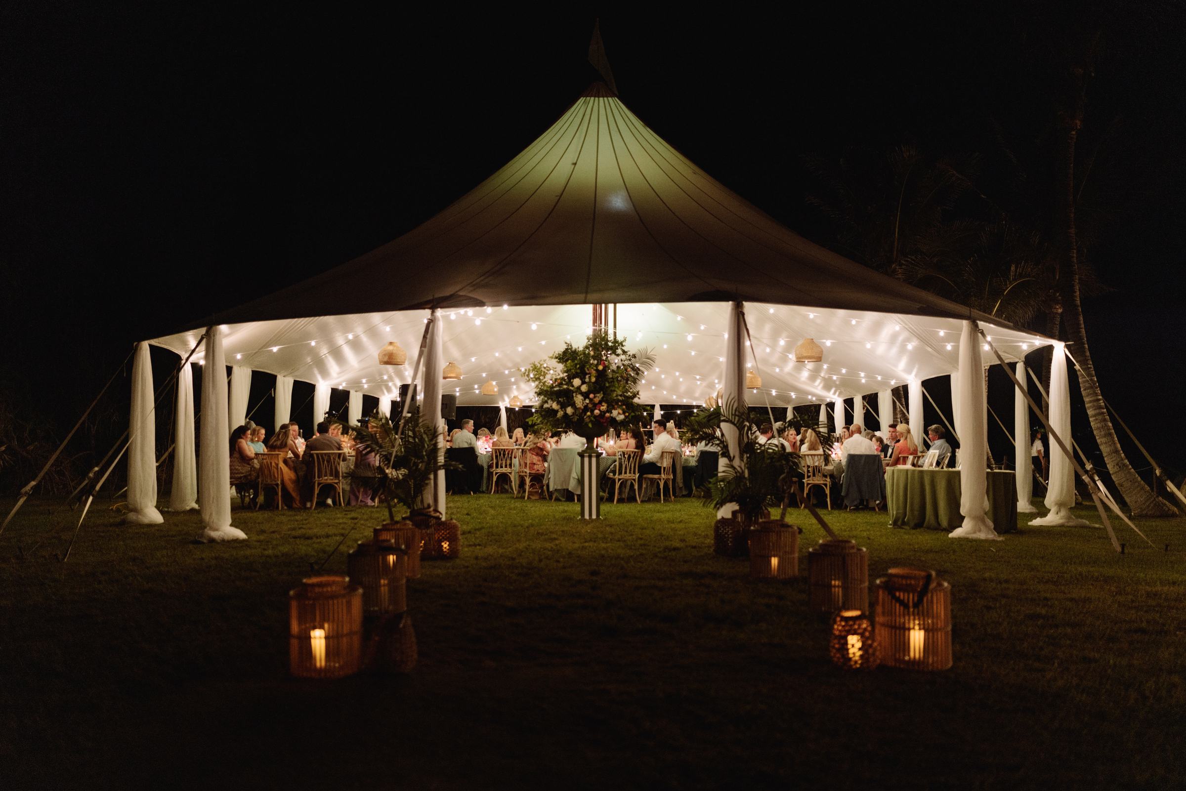 Sailcloth tent glowing with lanterns on the lawn at night