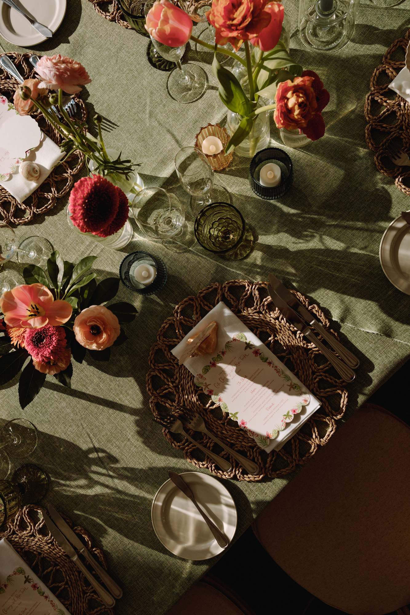 Overhead tablescape with green linen, coral flowers and candlelight