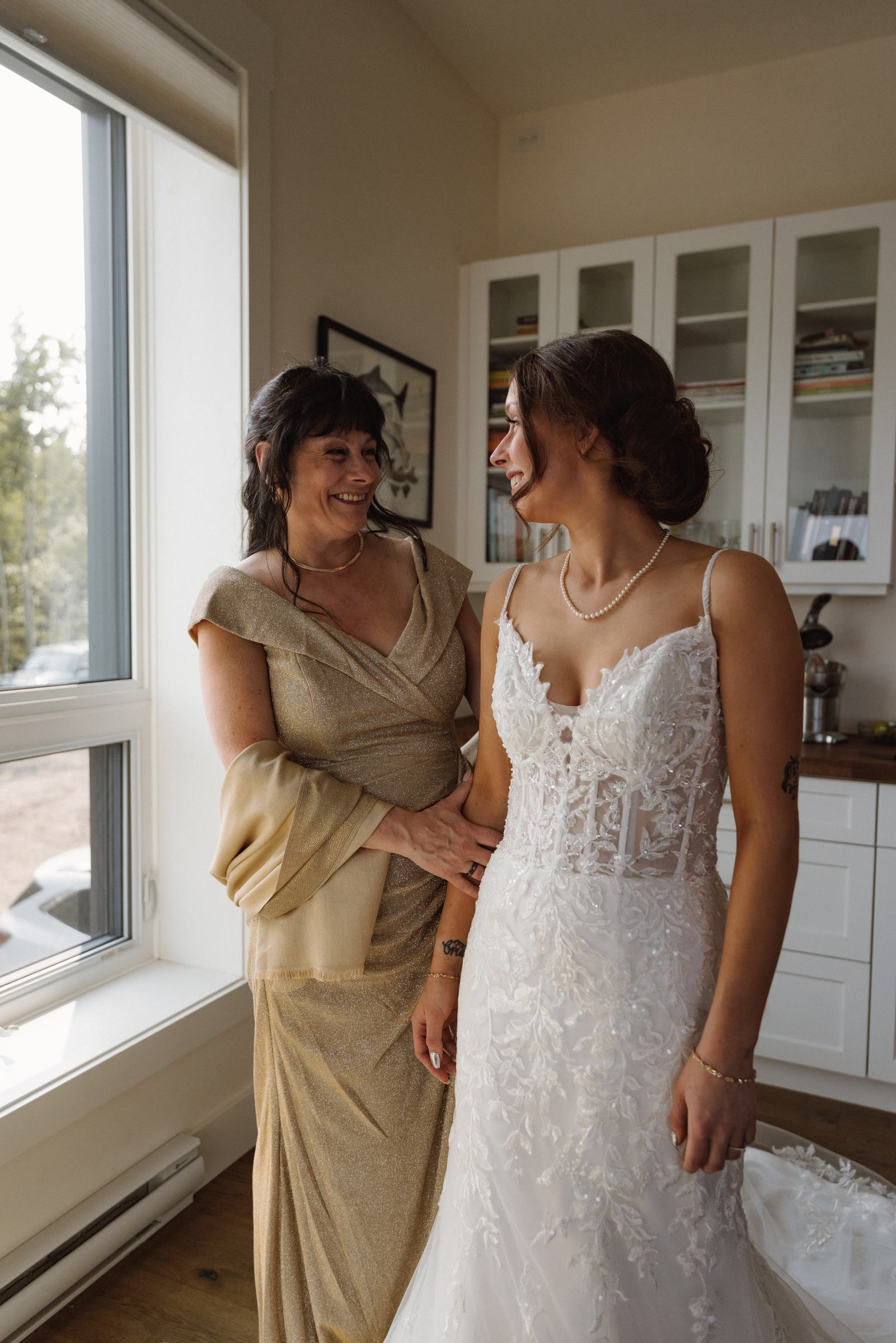 Bride with her mother in soft window light before the ceremony