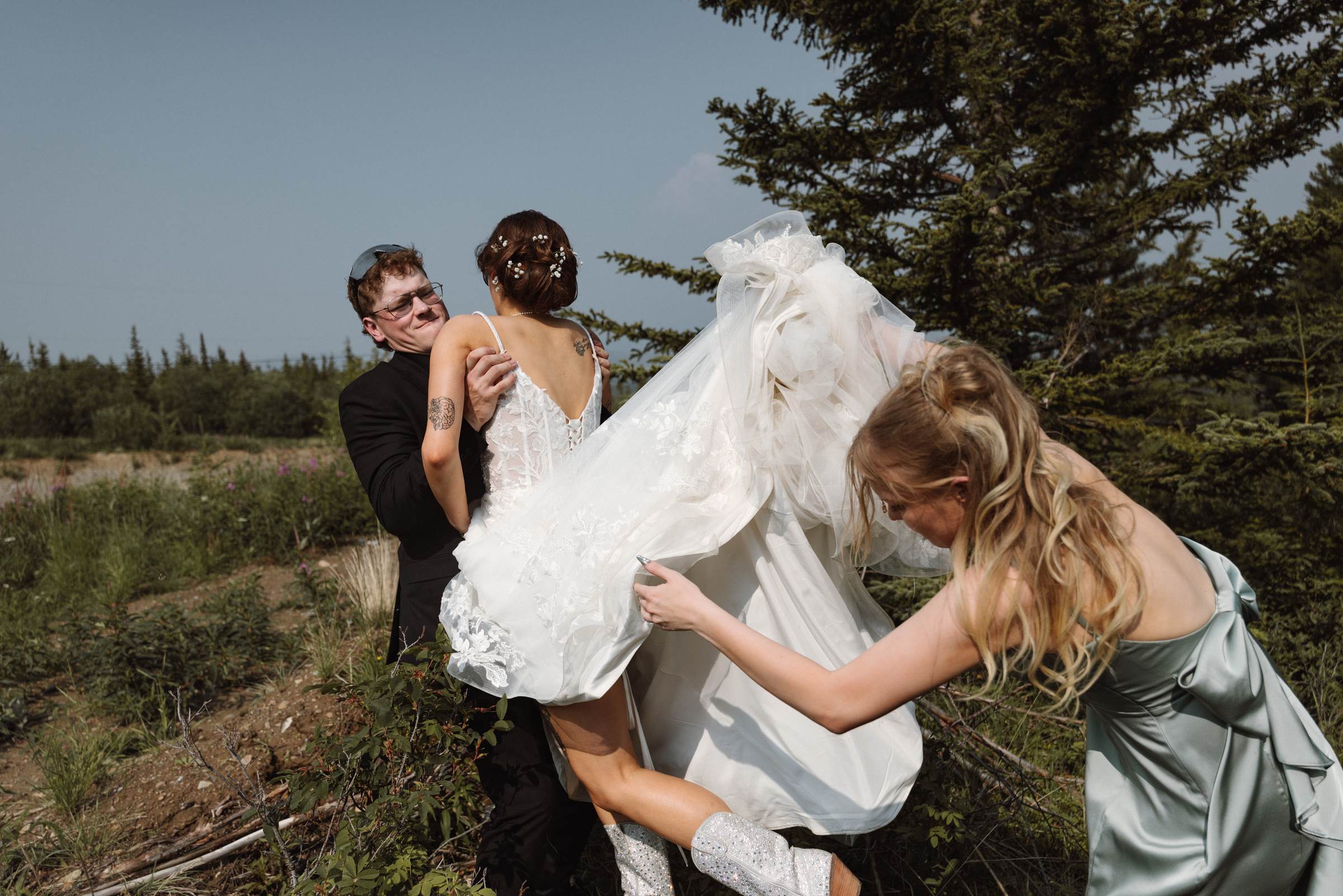 Wind catching the bride's veil as her friends laugh and help her