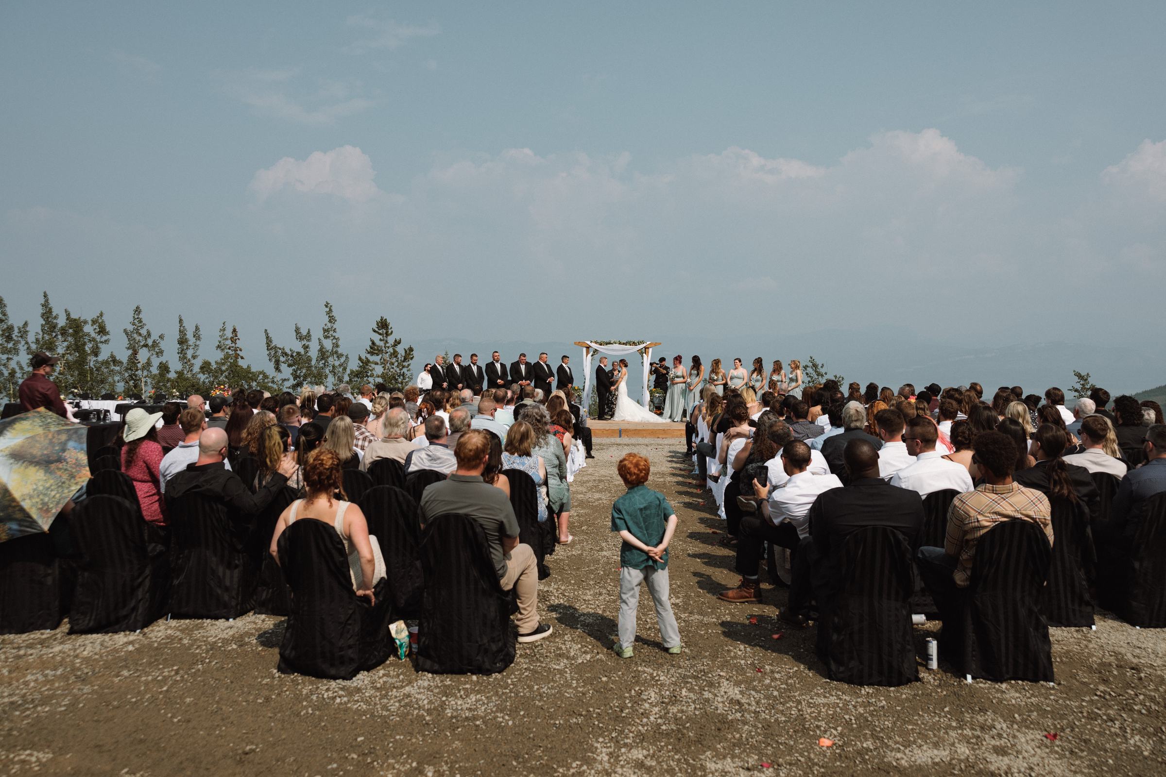Wide mountaintop ceremony seen from behind the seated guests