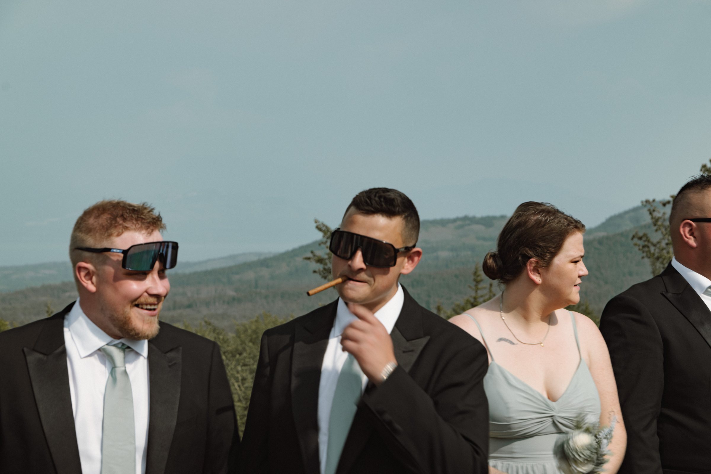 Groomsmen and a bridesmaid in sunglasses with a cigar during cocktail hour