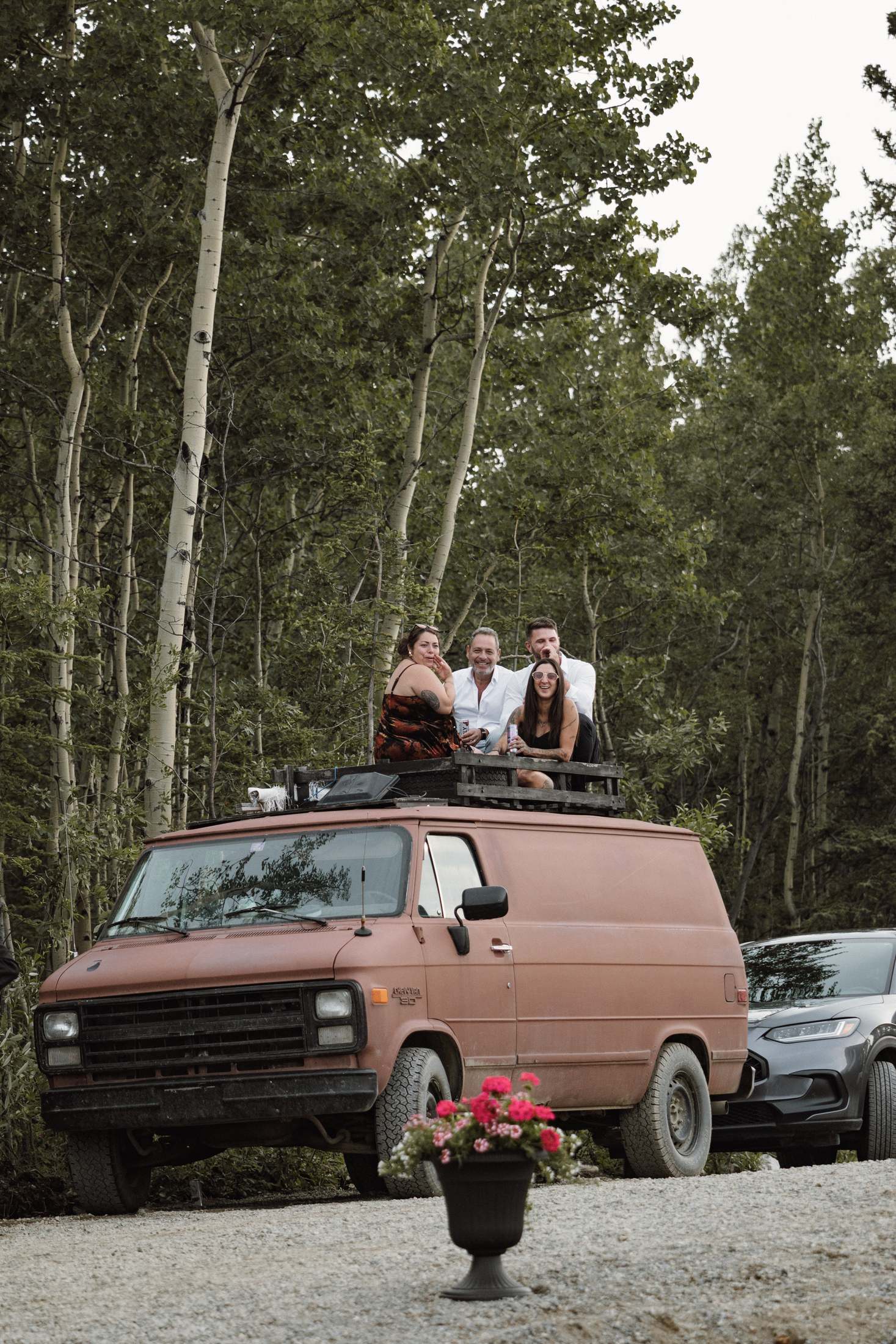 Guests sitting on the roof of a vintage van at a mountaintop wedding