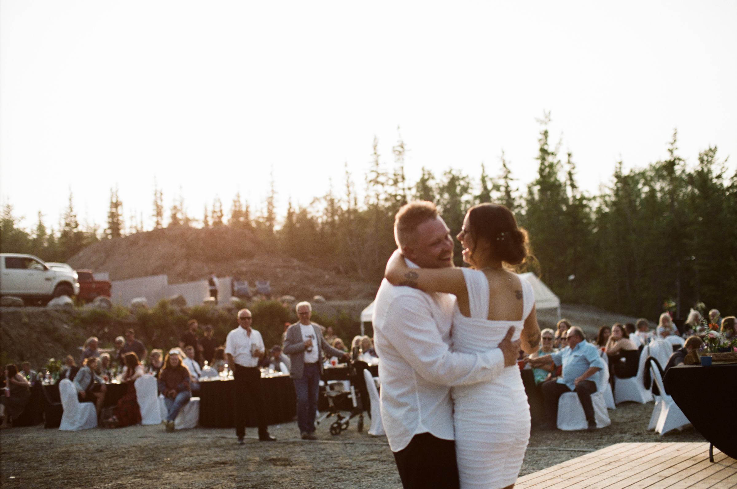 Bride and groom dancing at golden hour with guests and the valley behind them