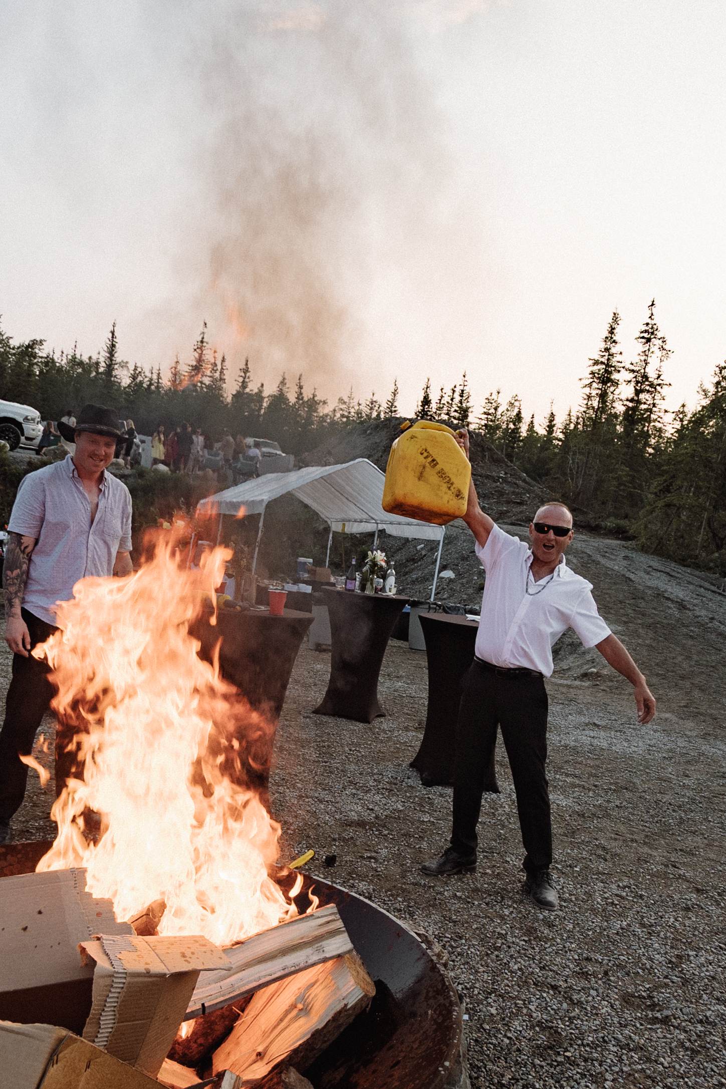 Guests gathered around a bonfire at dusk after a mountaintop wedding