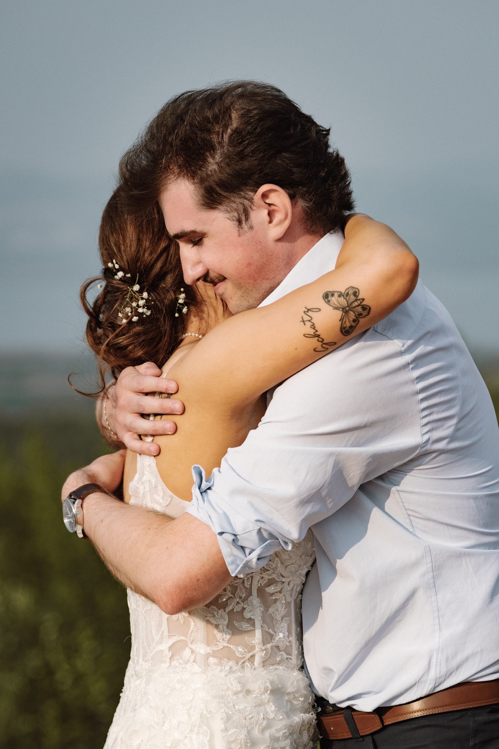 Bride and groom holding each other close with the northern hills behind them