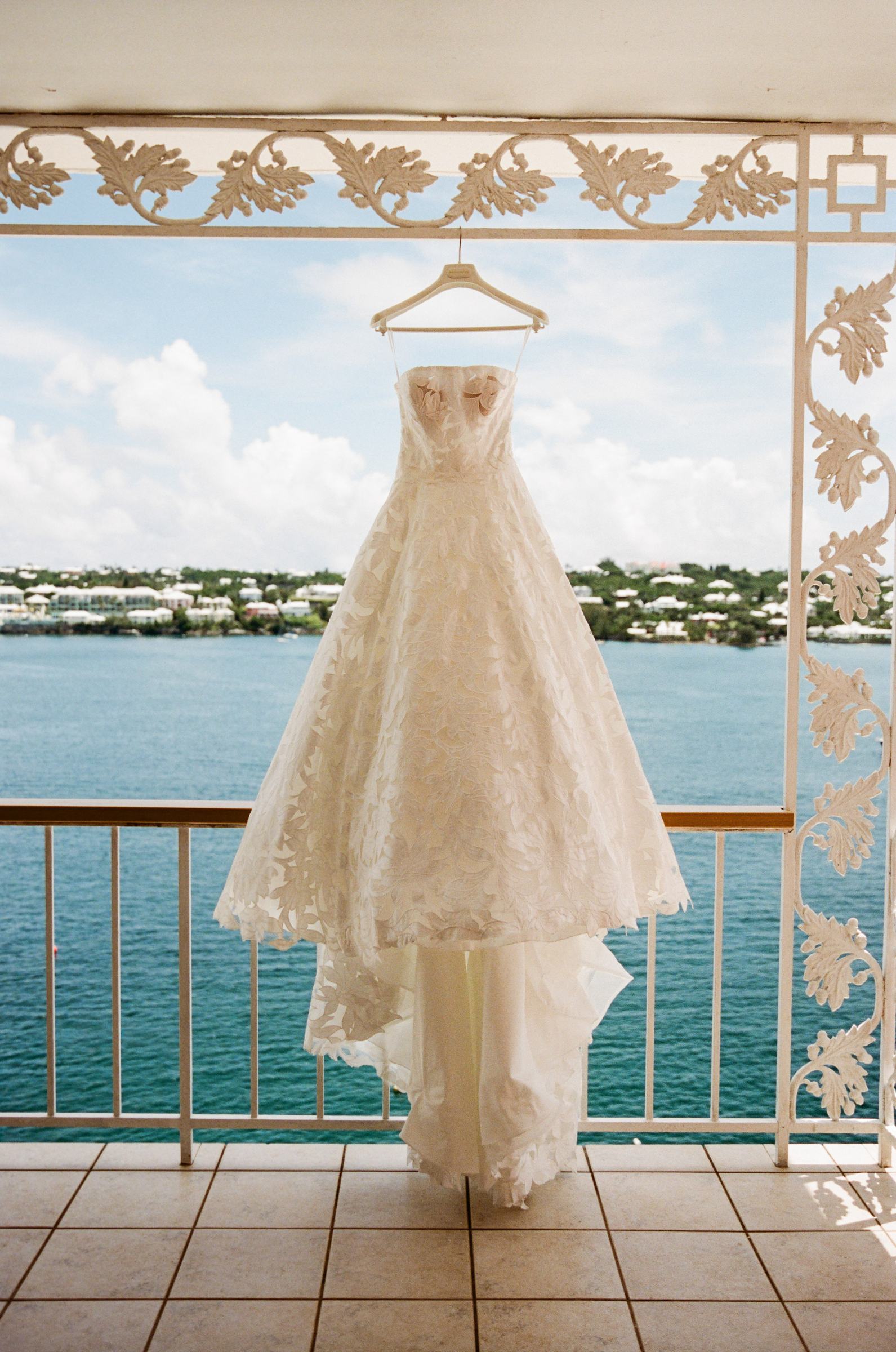 Wedding gown hanging in a doorway overlooking a Bermuda harbour, shot on film