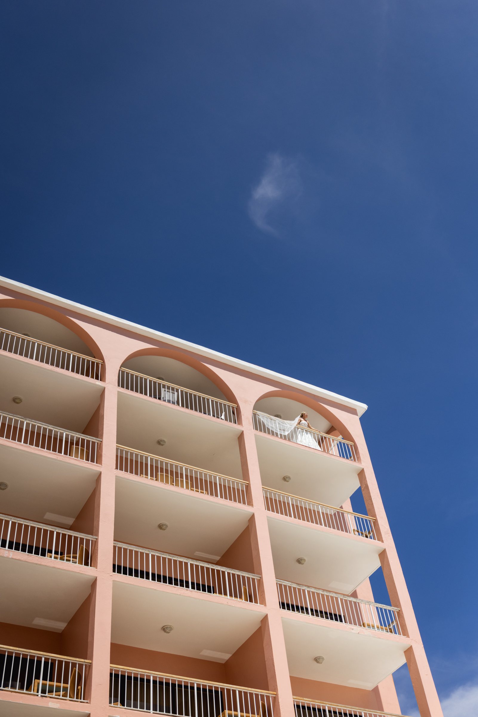 Coral pink Bermuda hotel facade against a deep blue sky