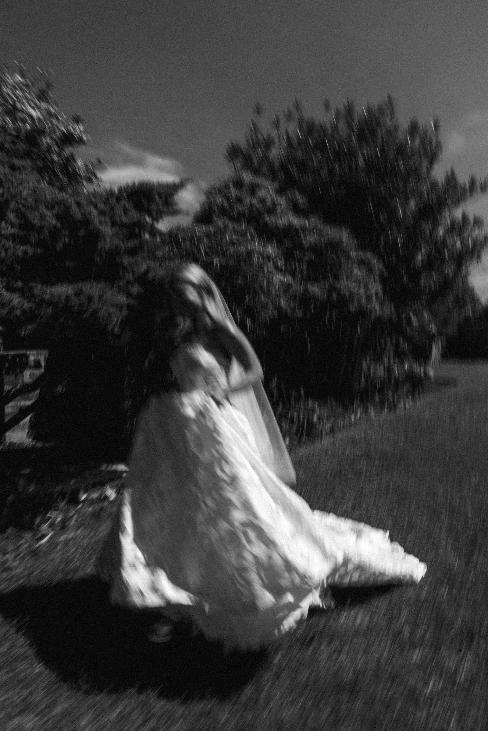 Black and white photograph of the bride spinning, her gown blurred with movement