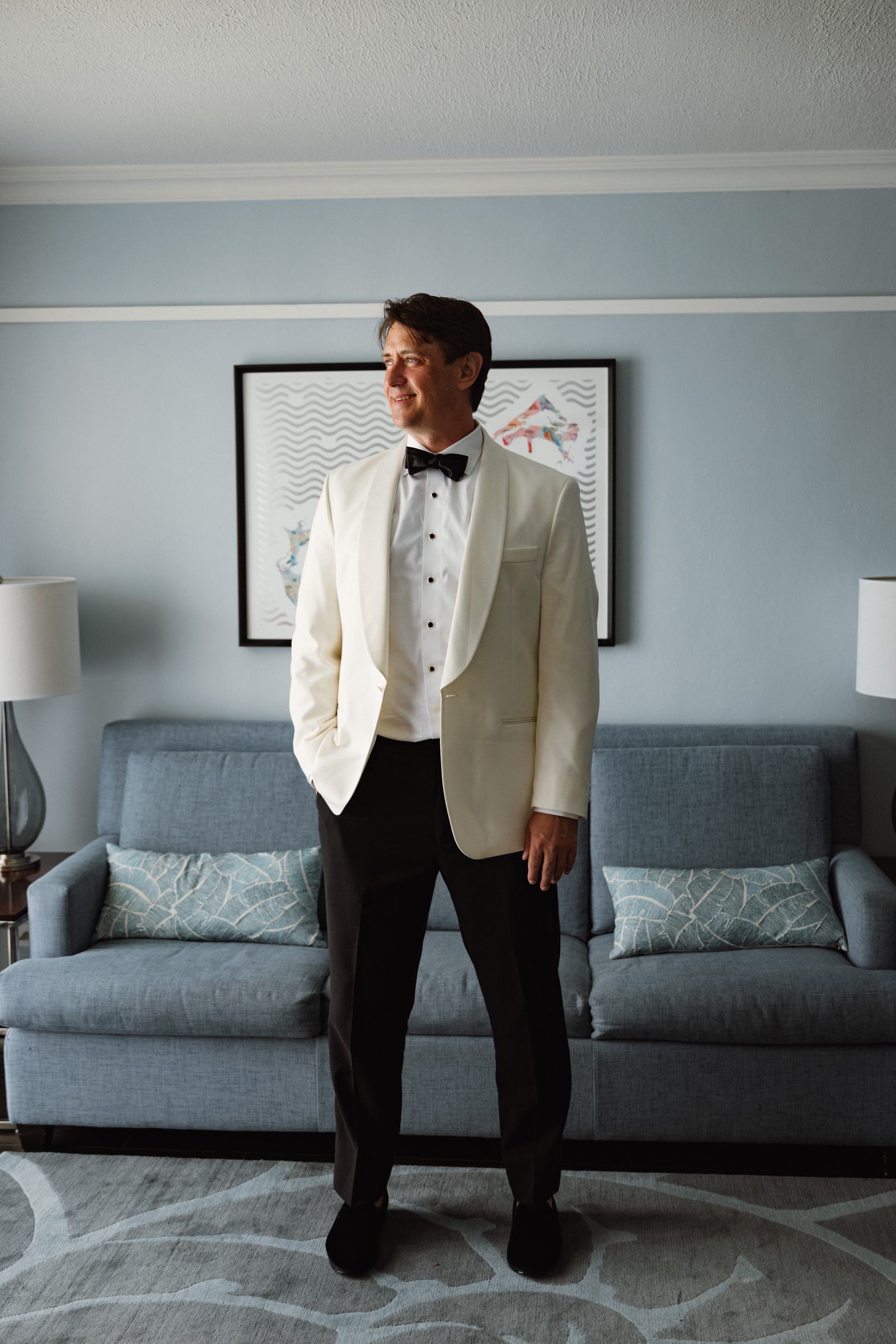 Groom in a white dinner jacket waiting in his room before the ceremony