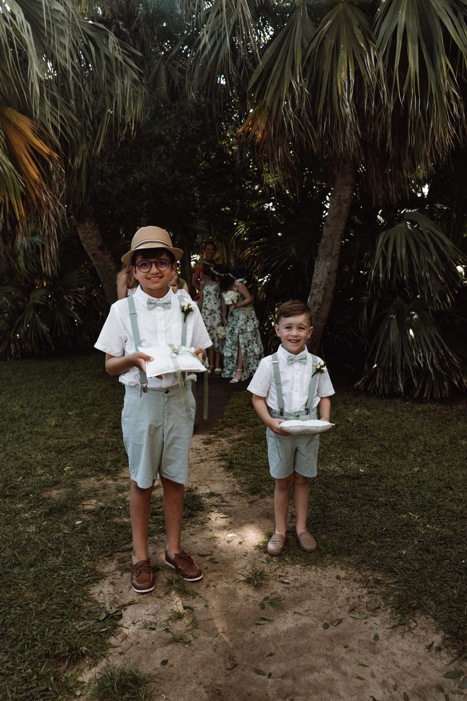 Two young page boys waiting under the palm trees before the ceremony