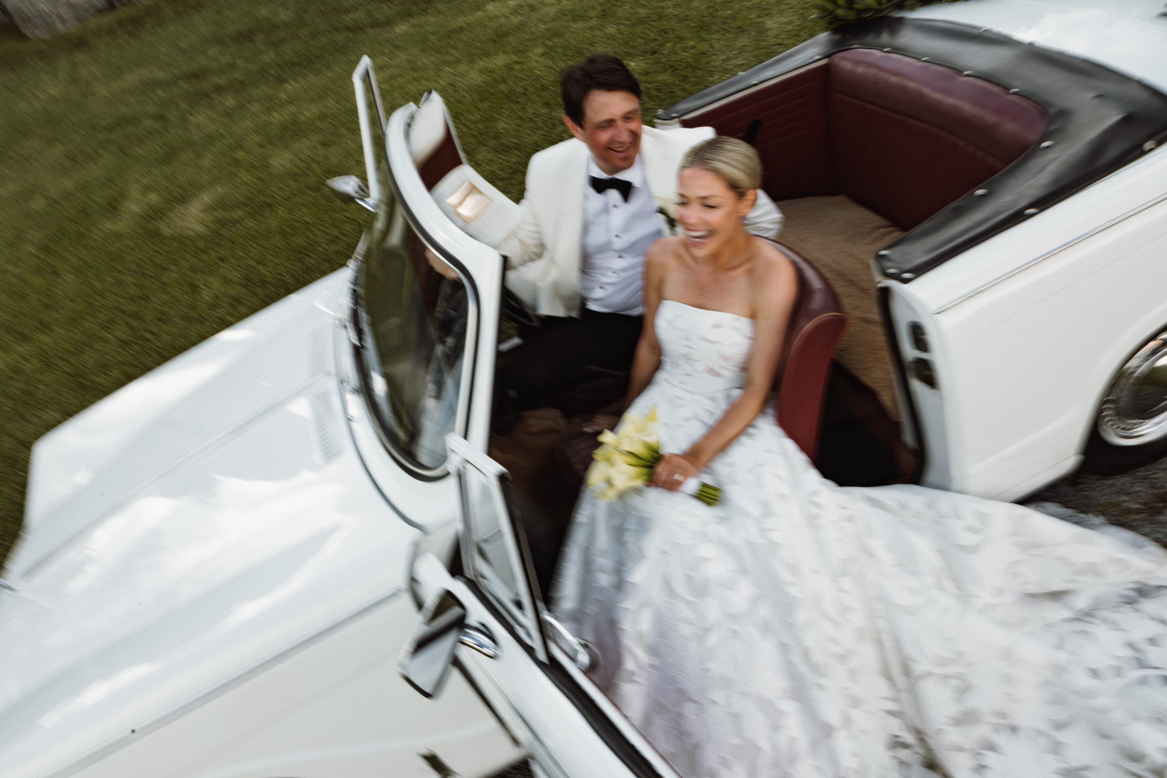 Bride and groom laughing in a white vintage convertible after their Bermuda wedding