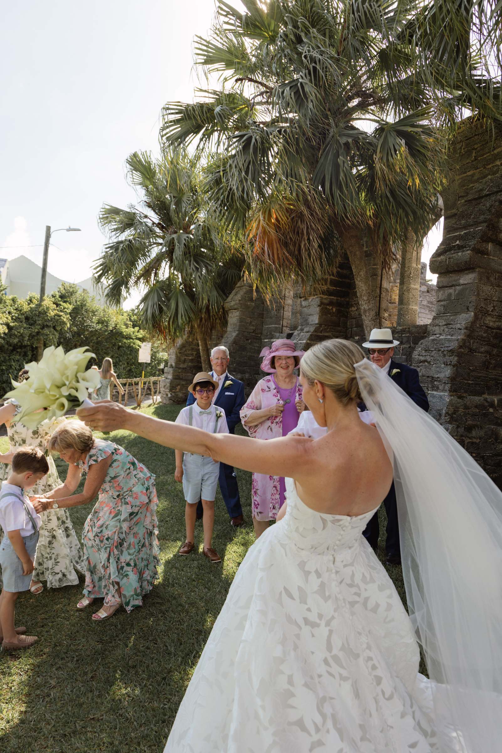 Bride reaching out to her guests during the recessional, veil catching the wind