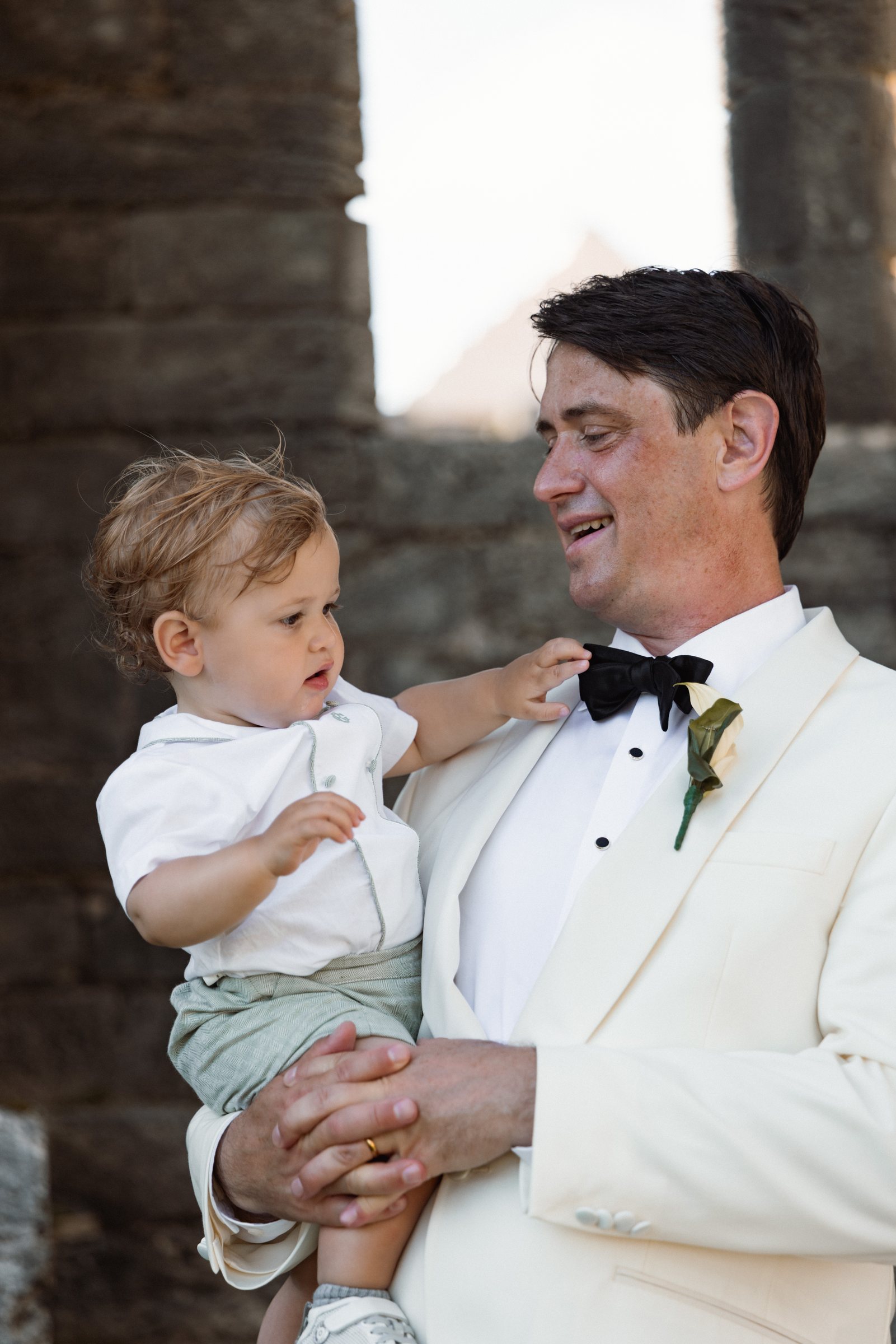 Groom holding a small boy in his arms at the Bermuda church ruins