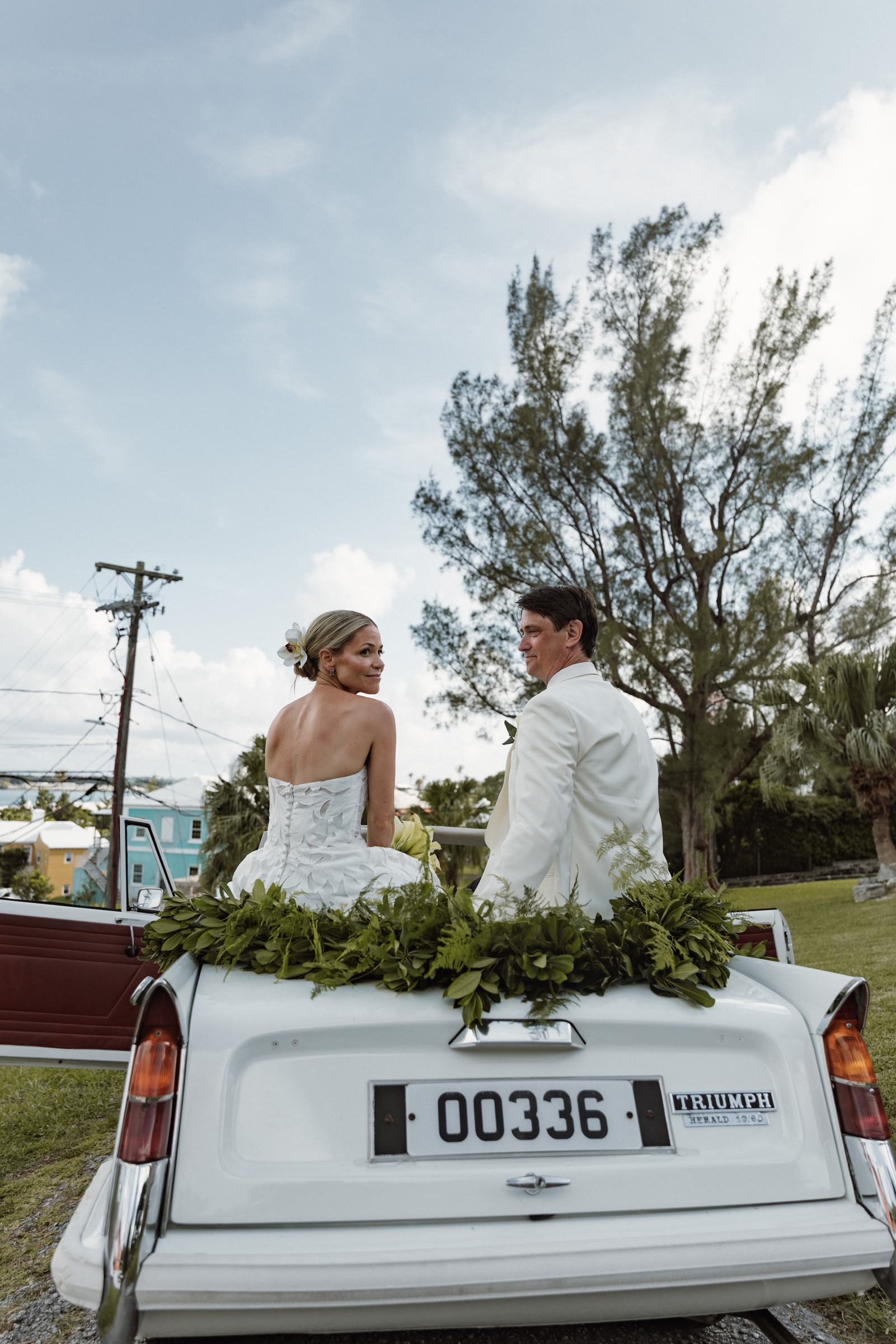 Bride and groom on the back of a white vintage convertible in Bermuda