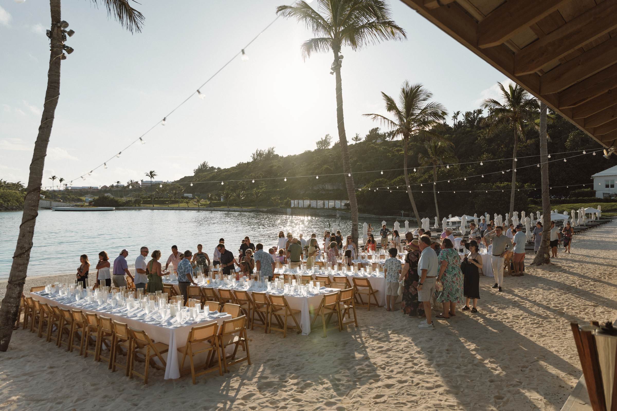 Long tables set on the sand for a Bermuda welcome party at sunset