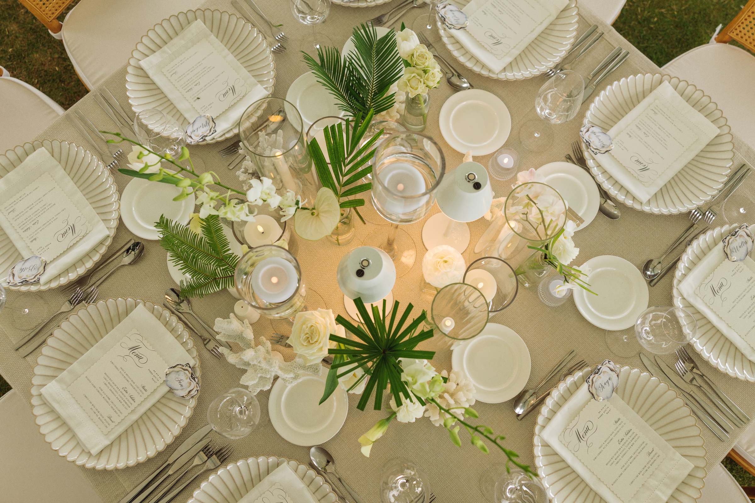 Overhead tablescape with palm fronds, candlelight and printed menus