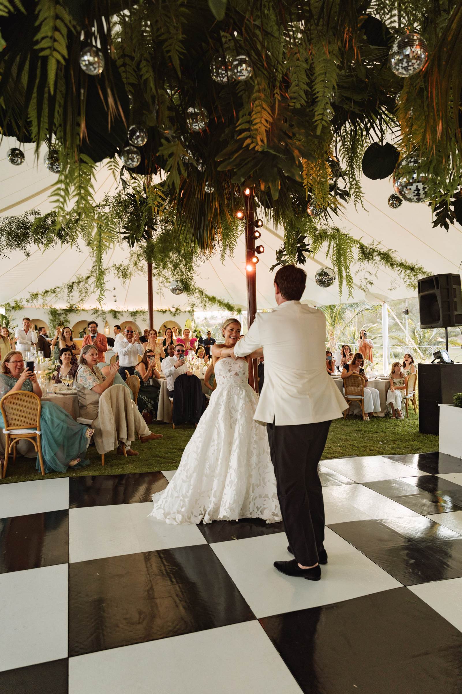 Bride and groom during their first dance under a greenery hung tent