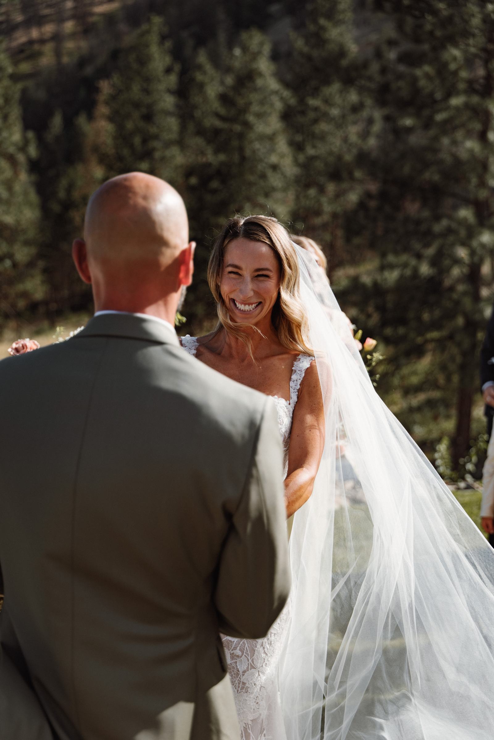 Bride and groom holding each other with her veil draped over his shoulder