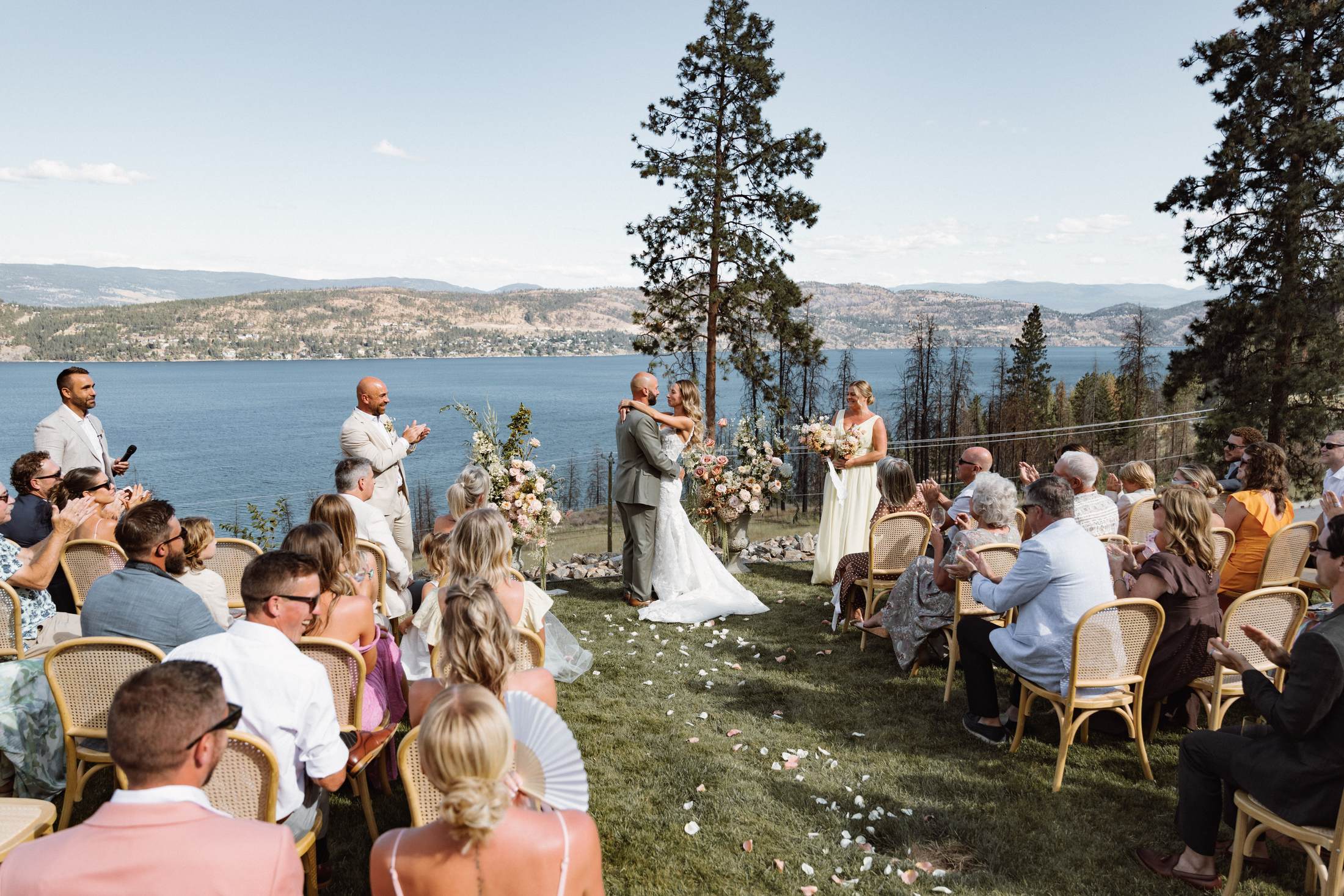 Wide hillside ceremony above the lake with the guests seated on the grass
