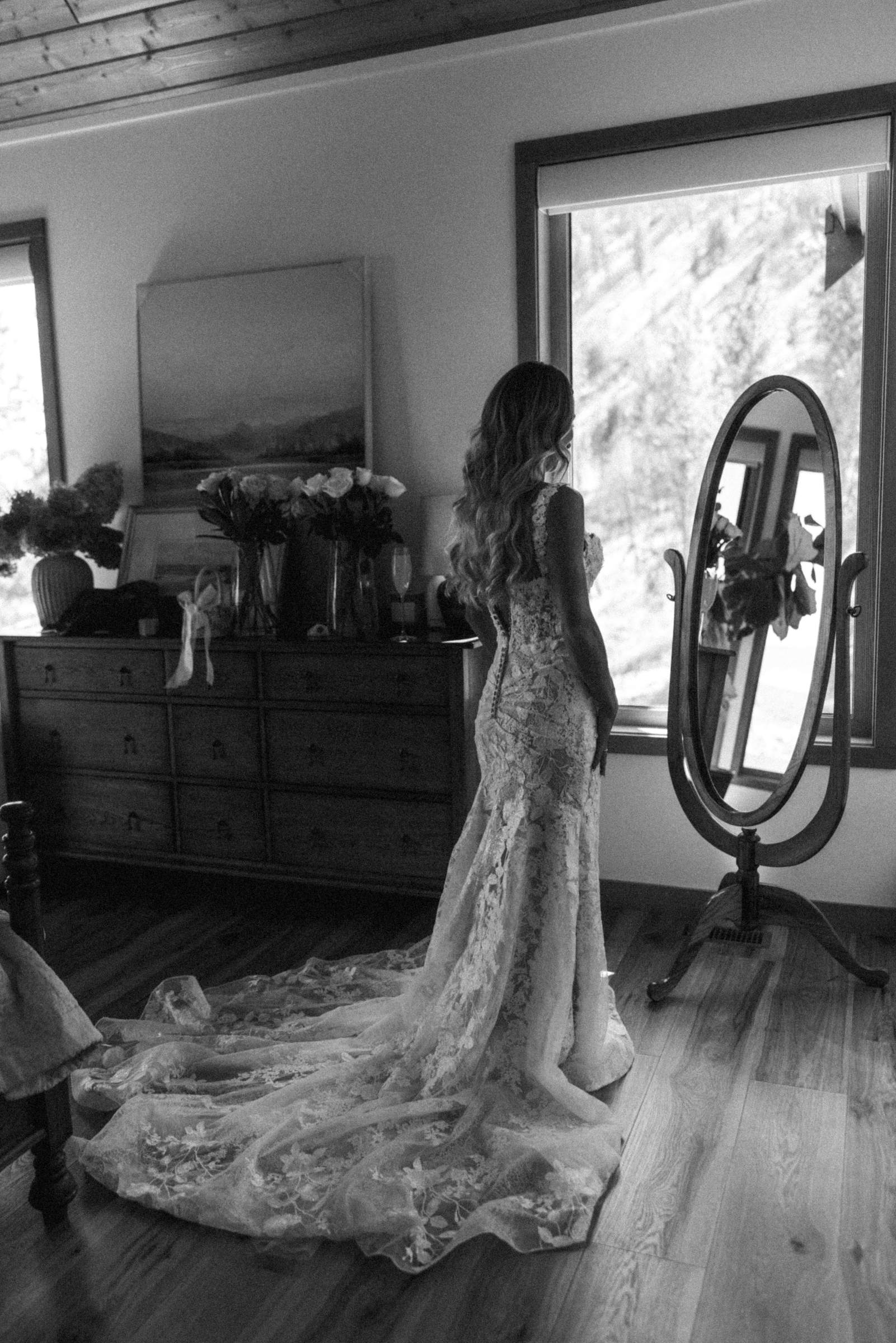 Black and white photograph of the bride and her gown reflected in the mirror