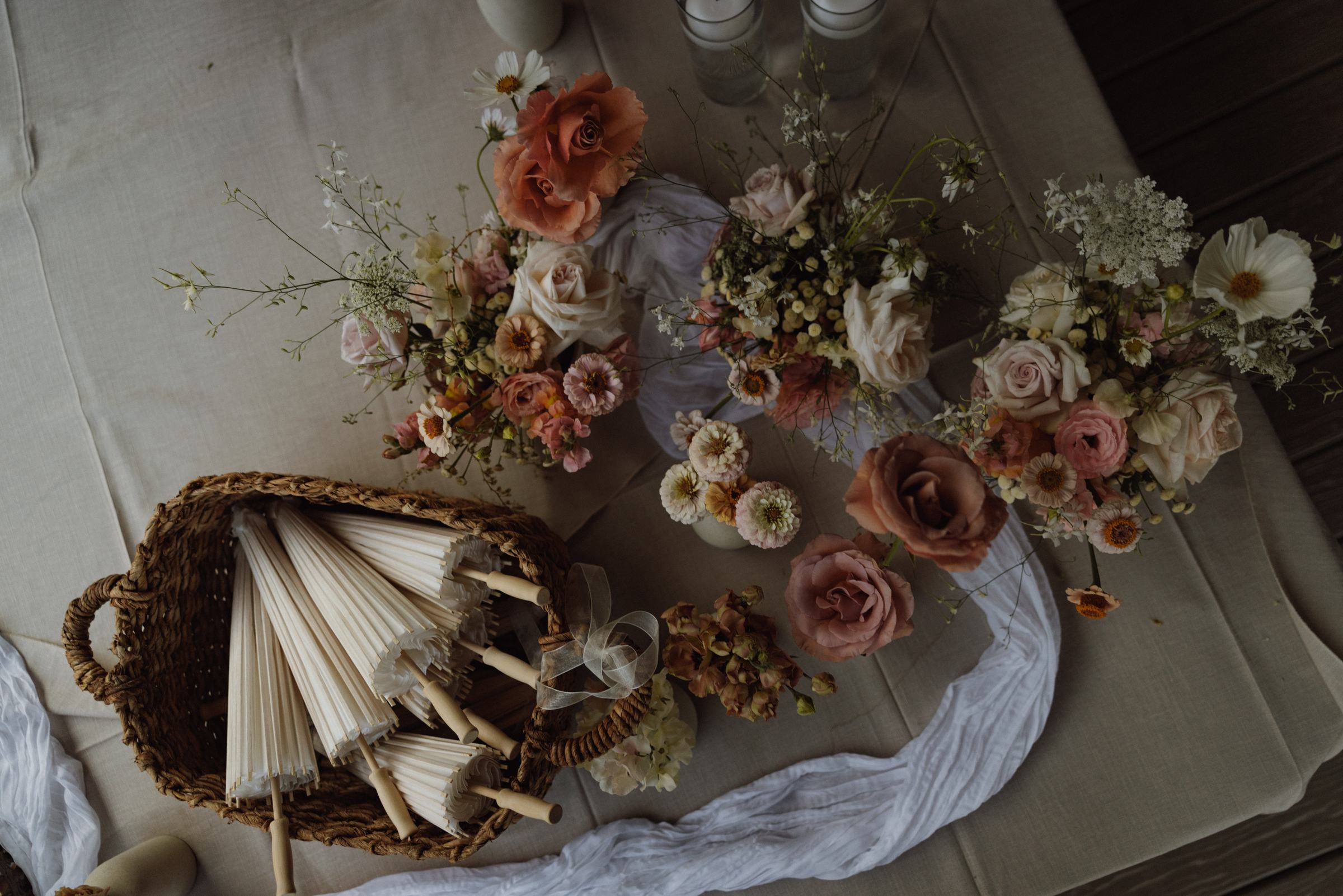 Overhead view of wedding florals and paper fans laid along the table