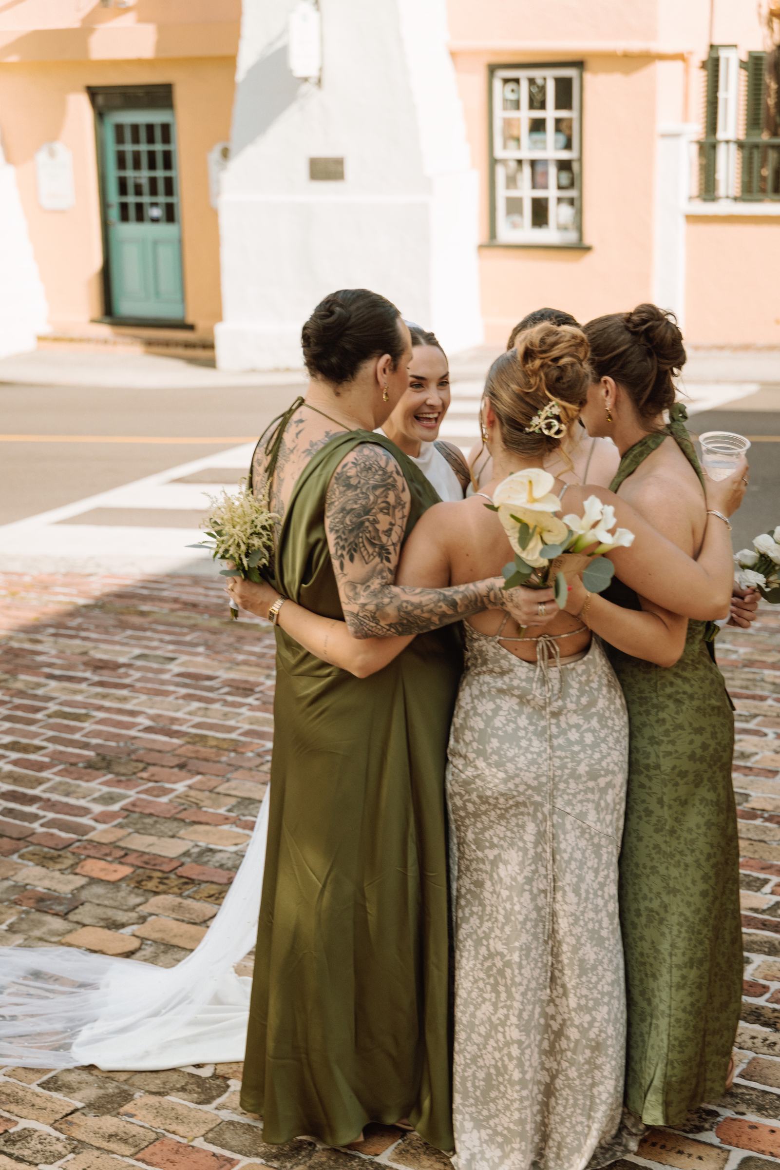 Bridesmaids in green embracing the bride on a Bermuda street