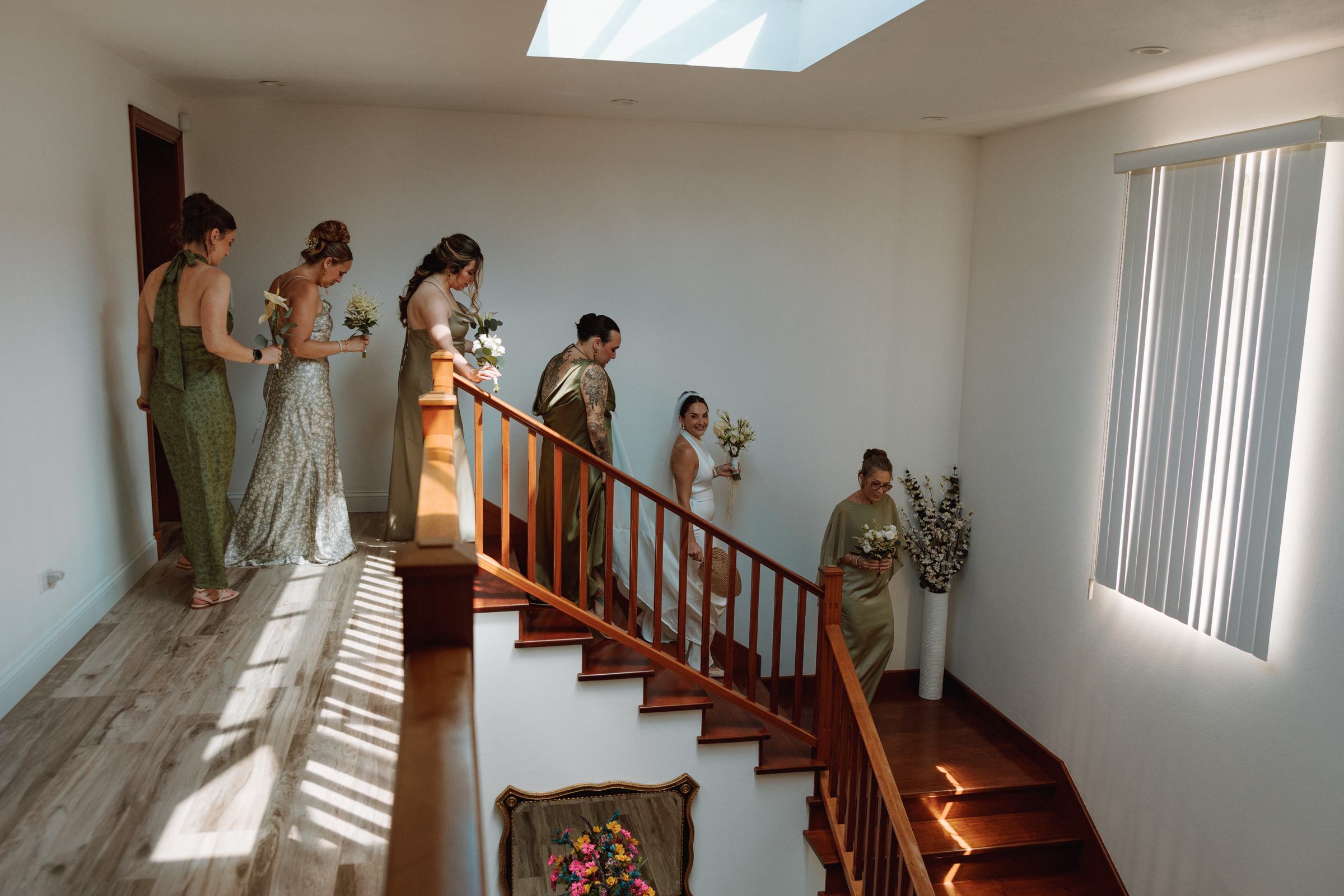 Bridesmaids in green coming down the staircase before a Bermuda wedding