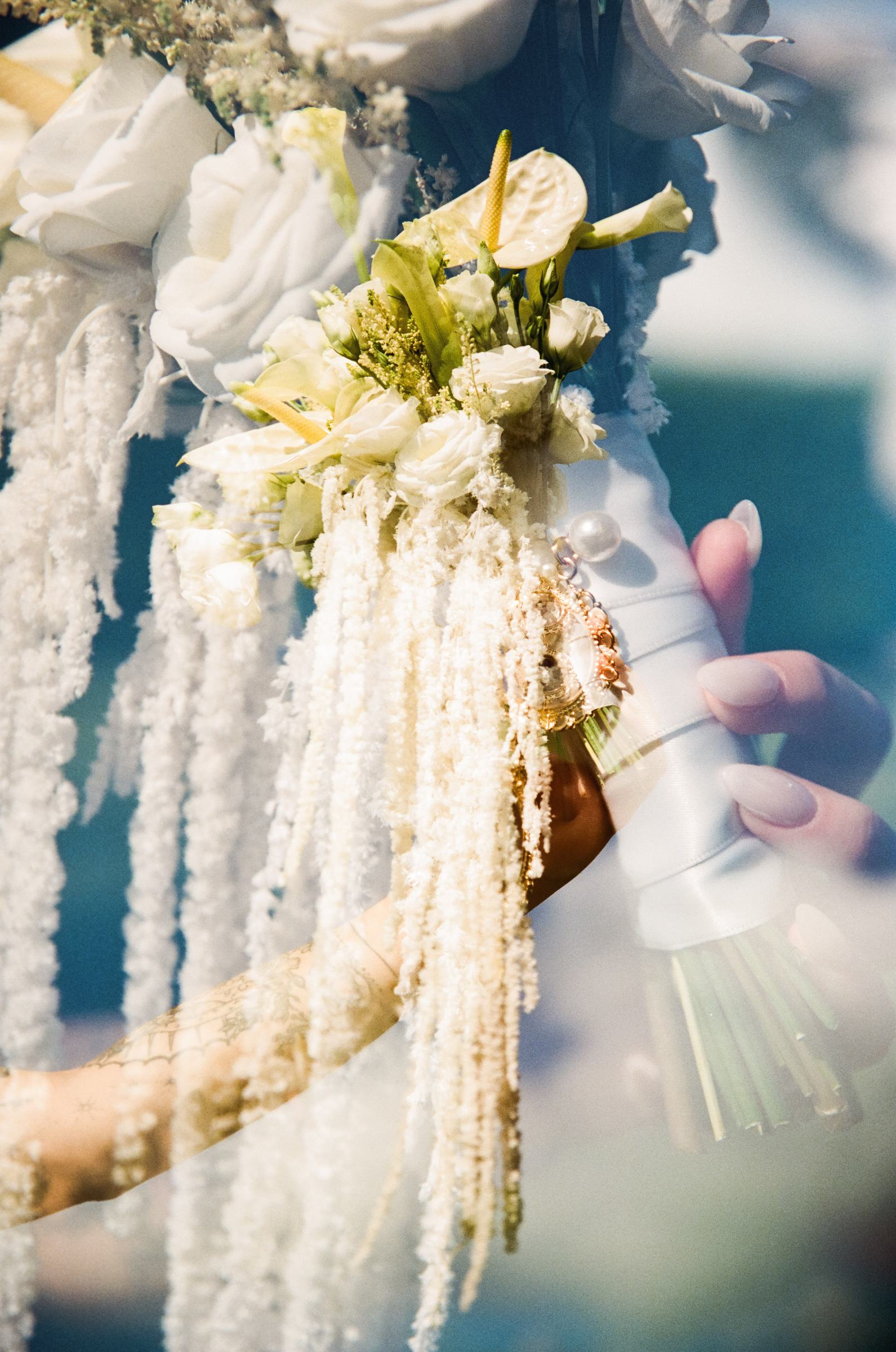 Detail of the bridal bouquet with white anthuriums and trailing greenery