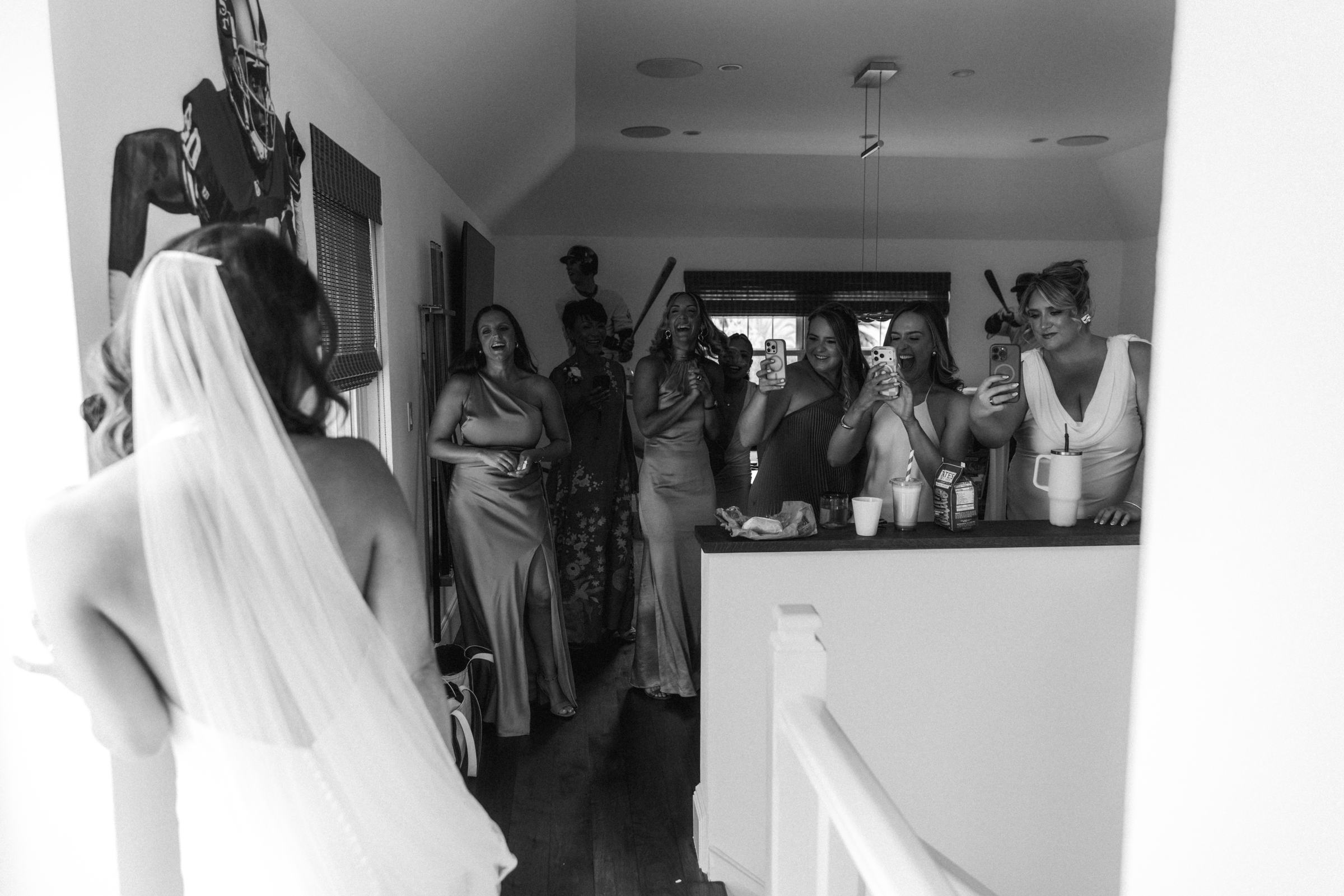 Black and white photograph of the bride at the top of the stairs with her veil over the rail