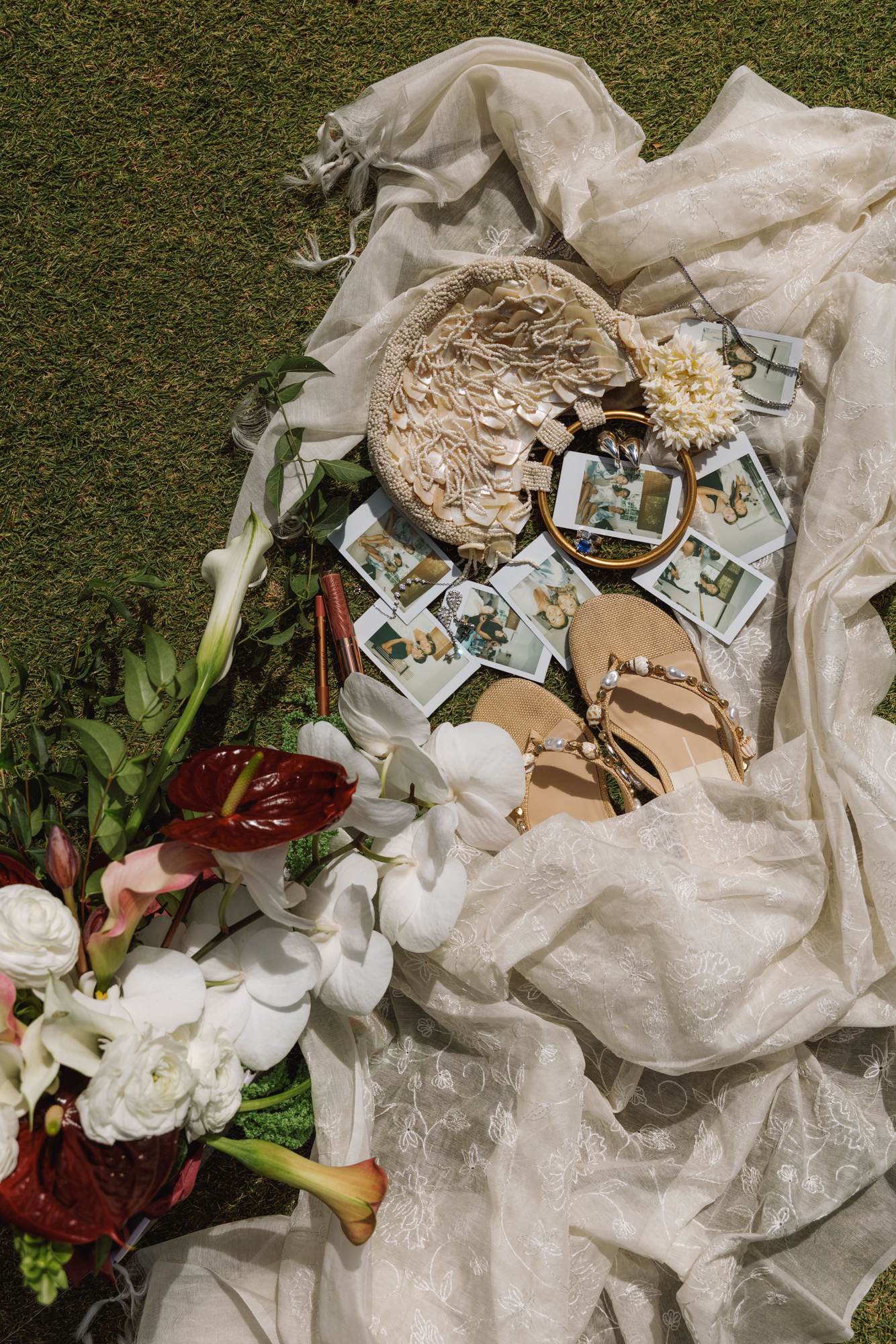 Flat lay of the wedding flowers, polaroids and invitation on the grass