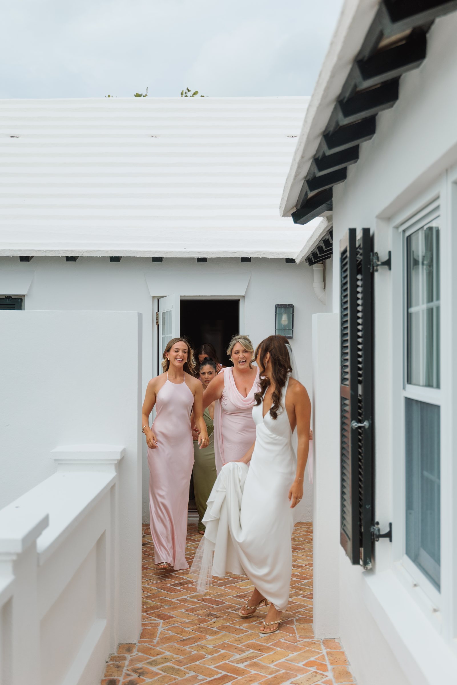 Bridesmaids in pink walking the path to a Bermuda beach ceremony